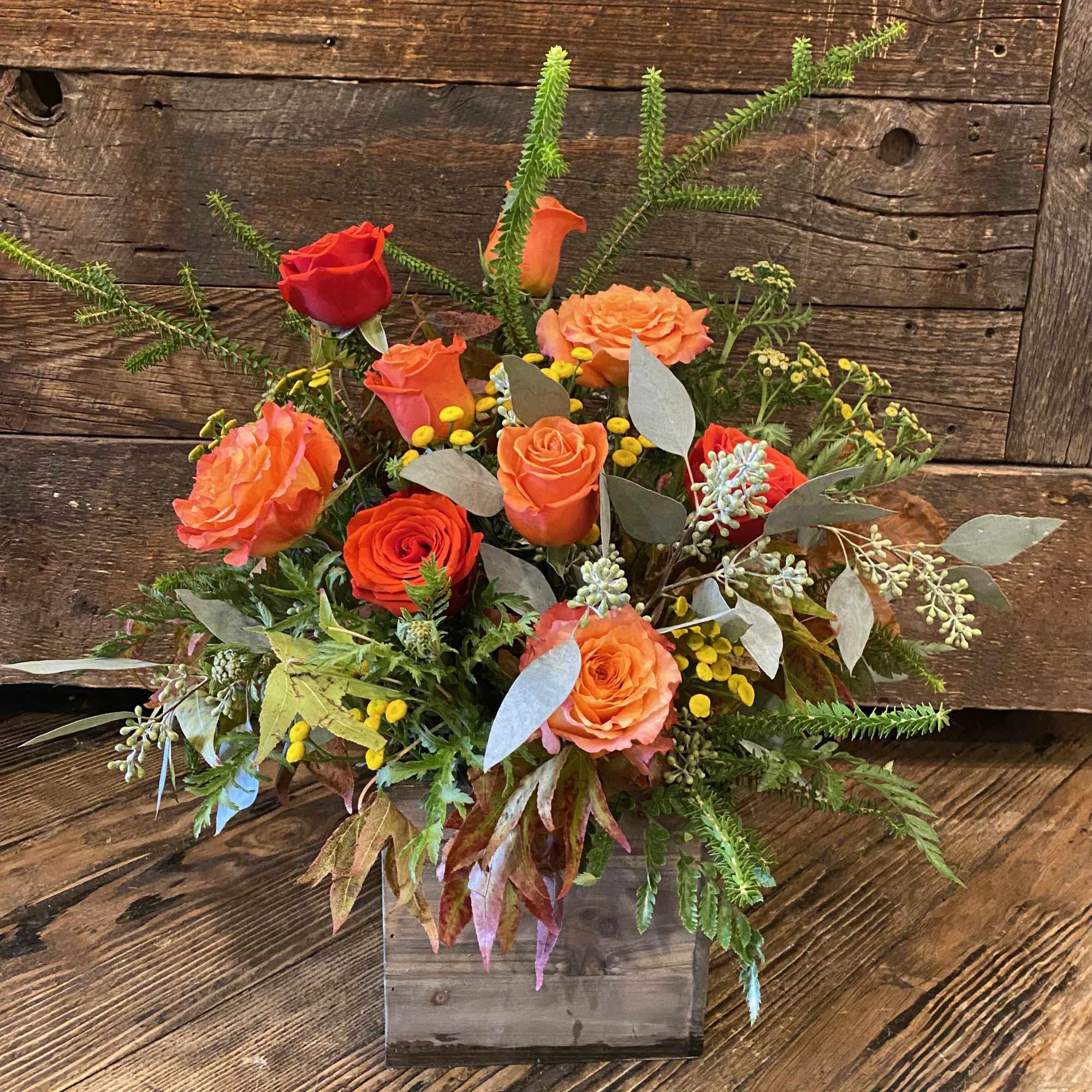 Orange and red roses in a rustic wooden box arrangement