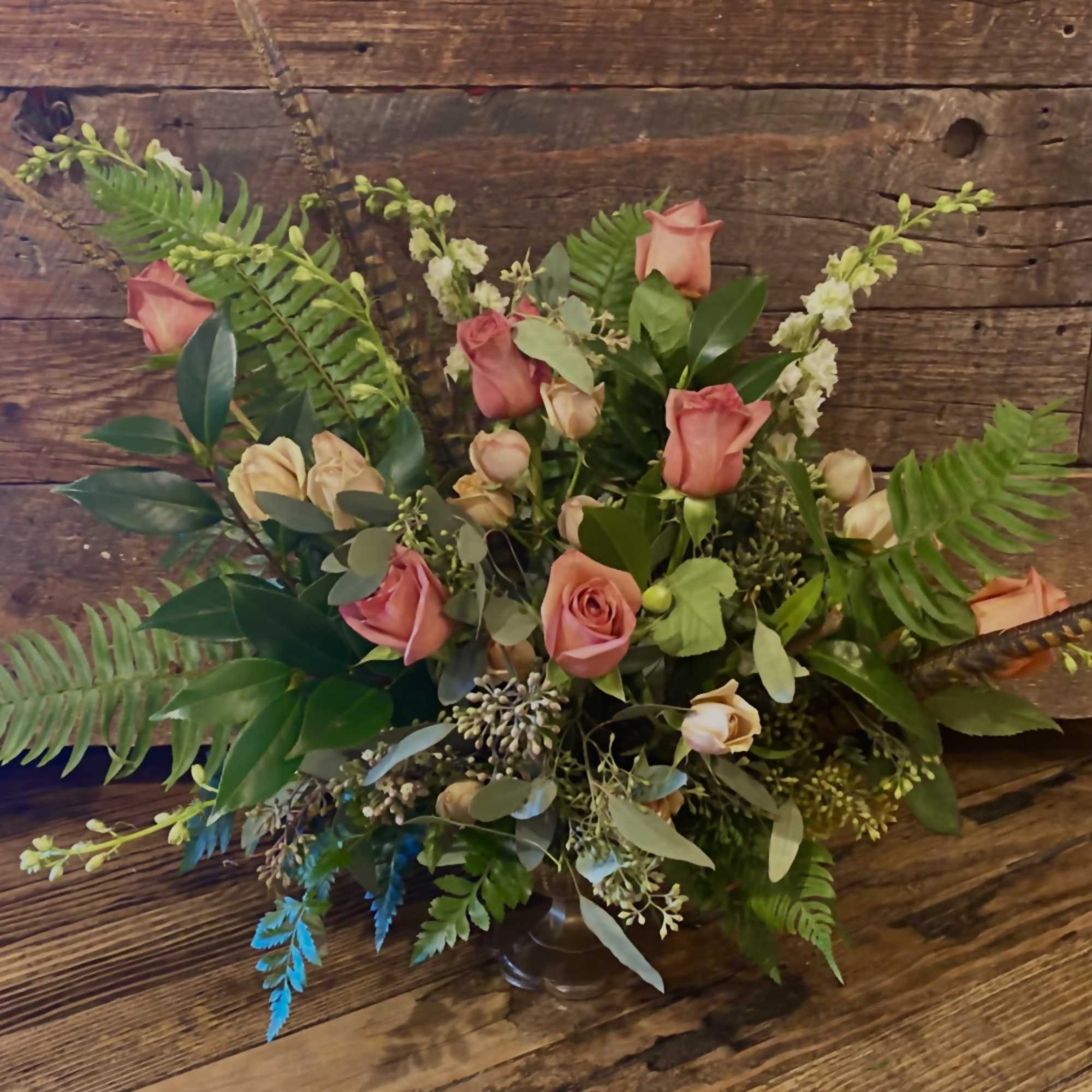 Pink roses in a low vase arrangement with mixed greenery