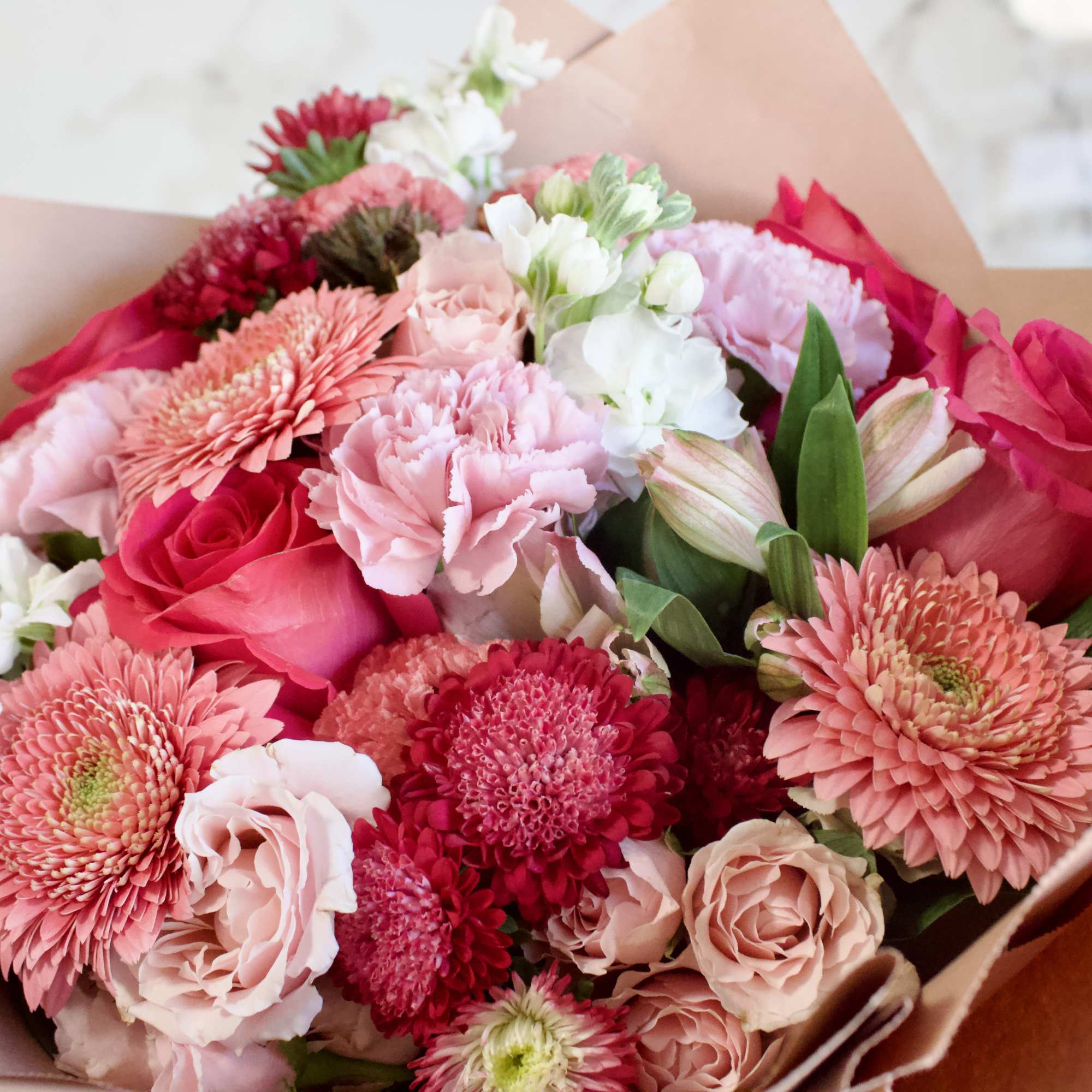 Bouquet of pink and white flowers wrapped in brown paper