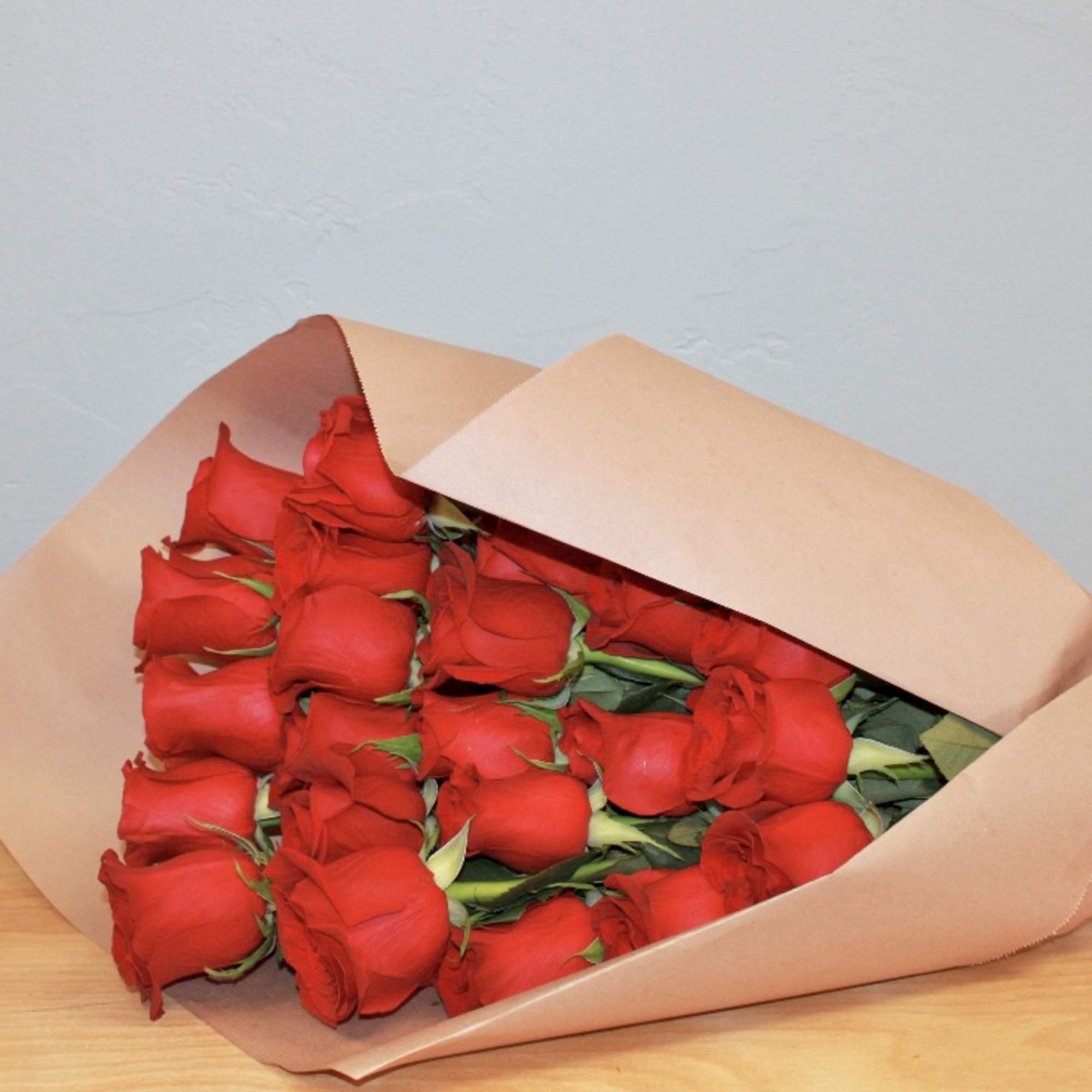 Bouquet of red roses wrapped in tan paper with a red ribbon