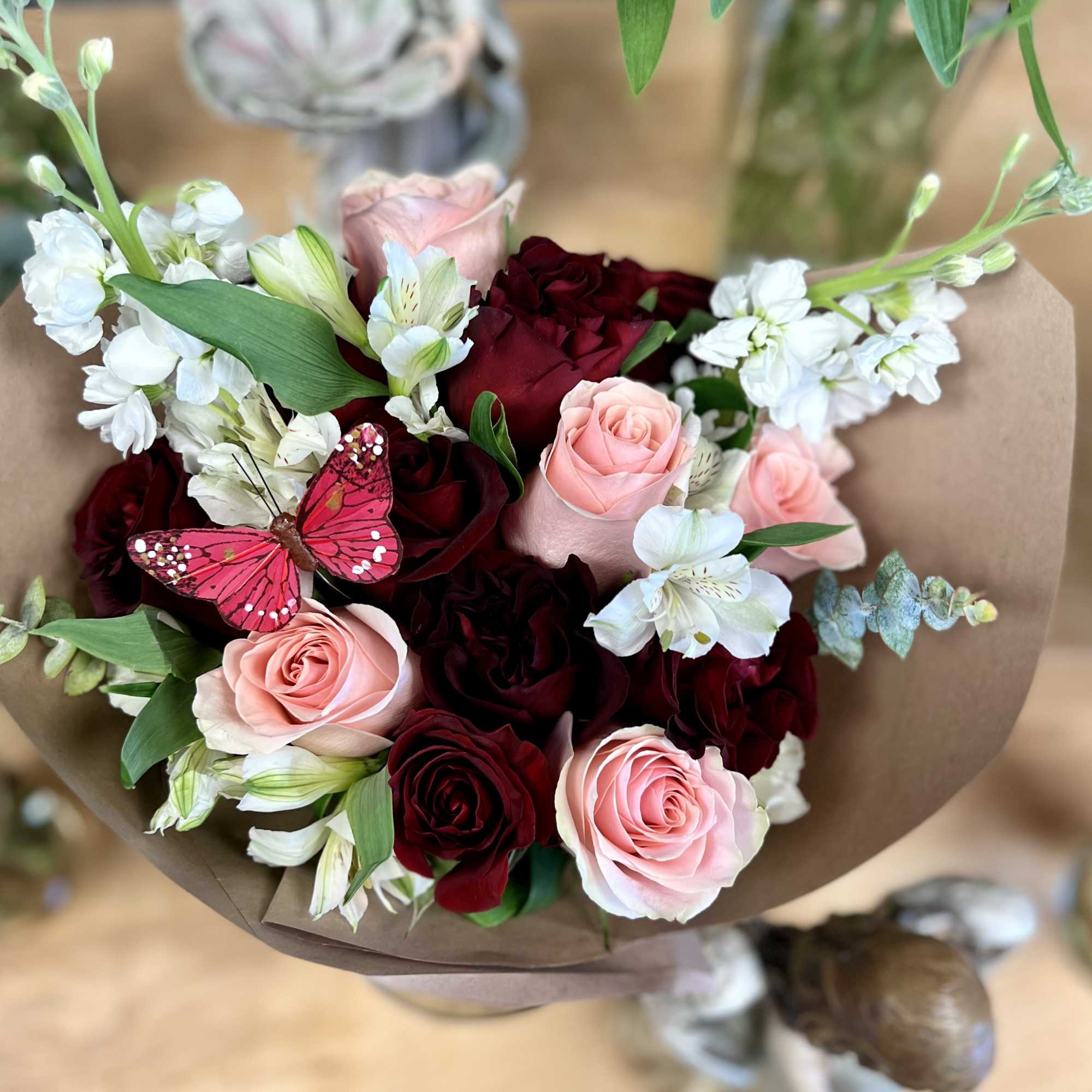 Bouquet of pink and deep red roses with white flowers wrapped in brown paper