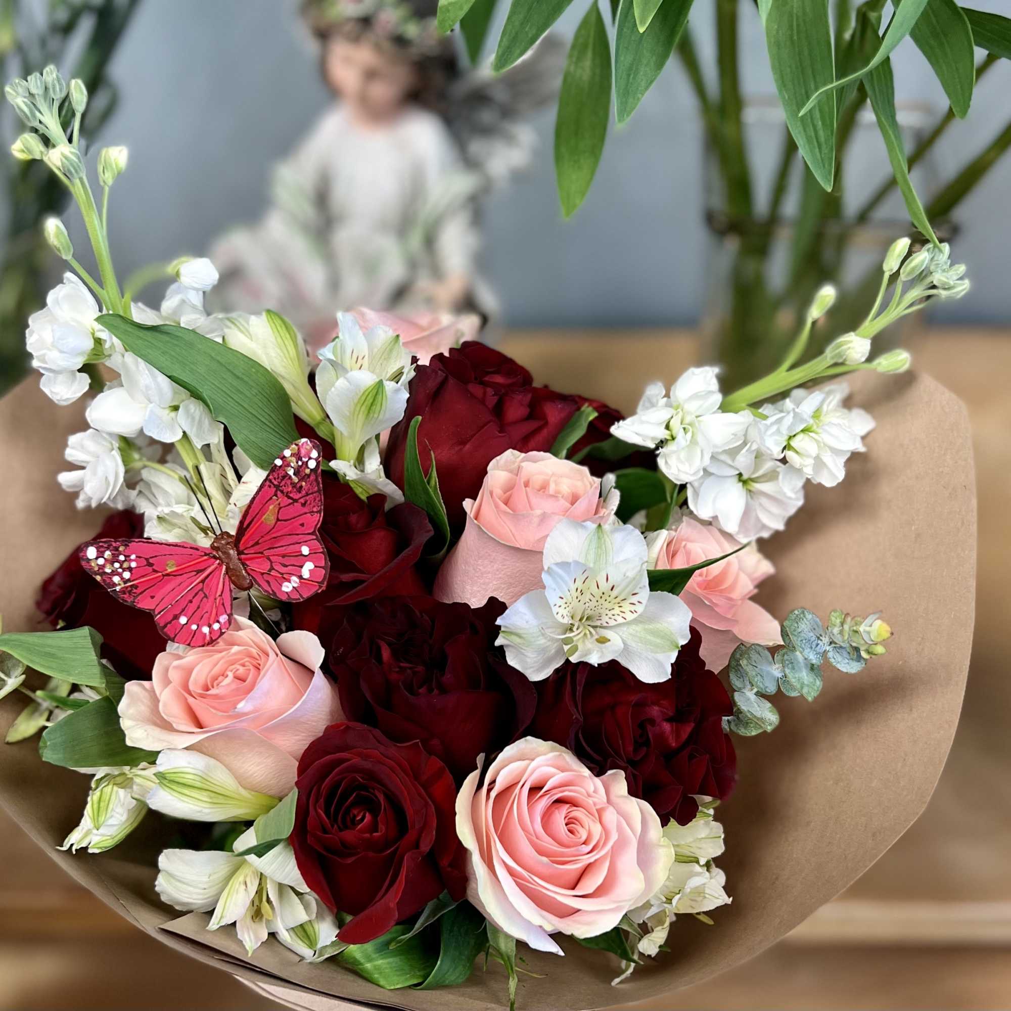 Bouquet of red and pink roses with white flowers and a pink butterfly decoration