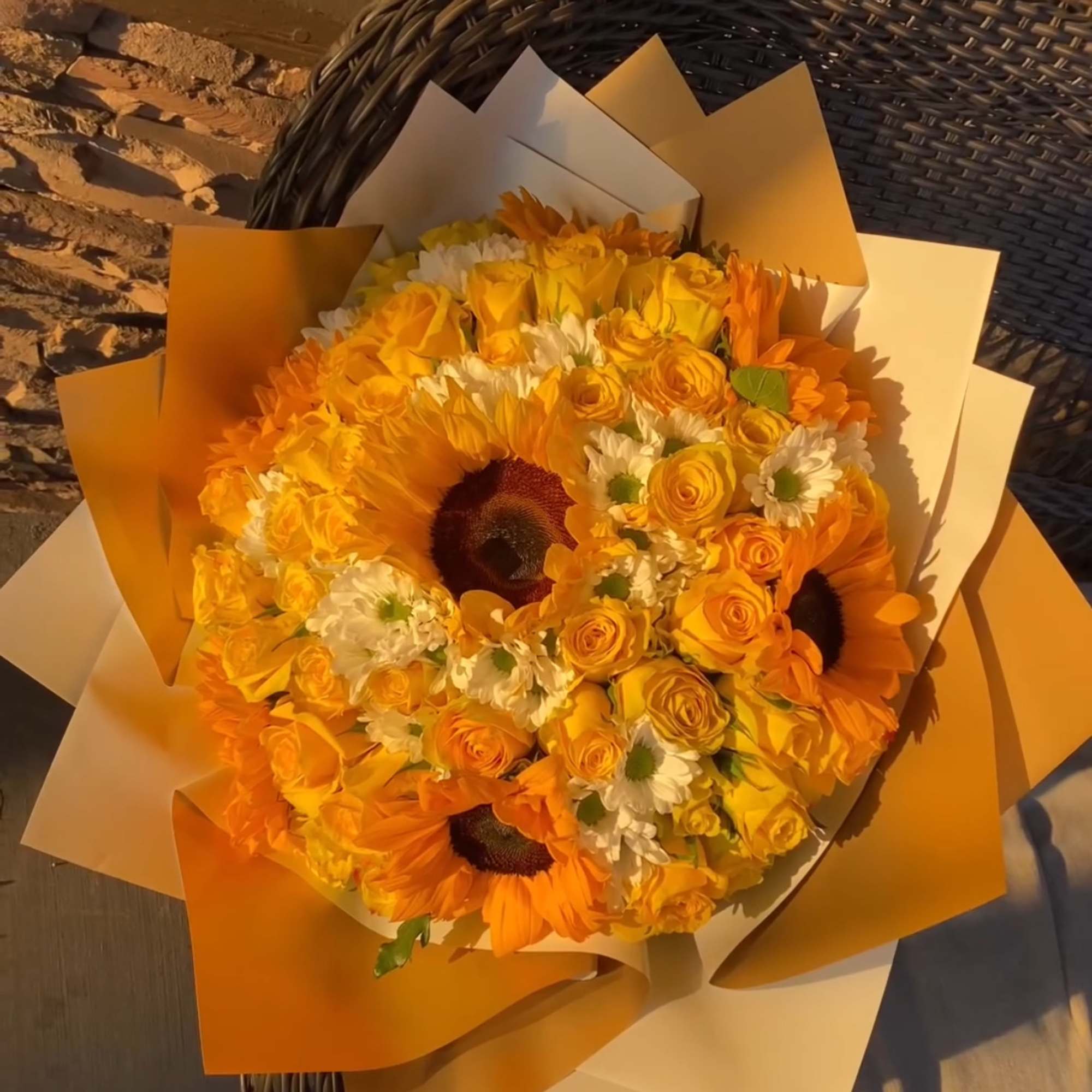Orange bouquet with sunflowers, yellow roses, and white daisies in paper wrap