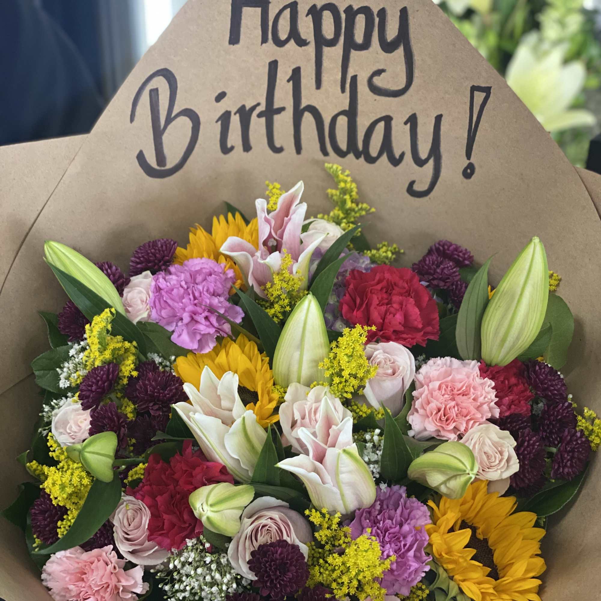 Mixed bouquet with a Happy Birthday sign and colorful blooms in kraft paper