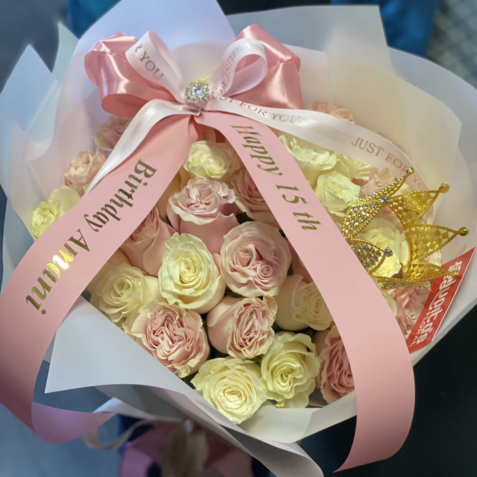 Bouquet of pale pink and cream roses with a pink birthday ribbon