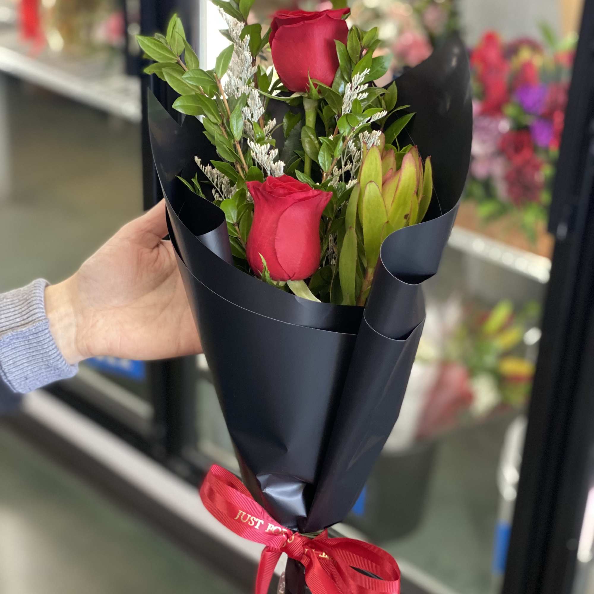 Bouquet of red roses wrapped in black paper with a red ribbon