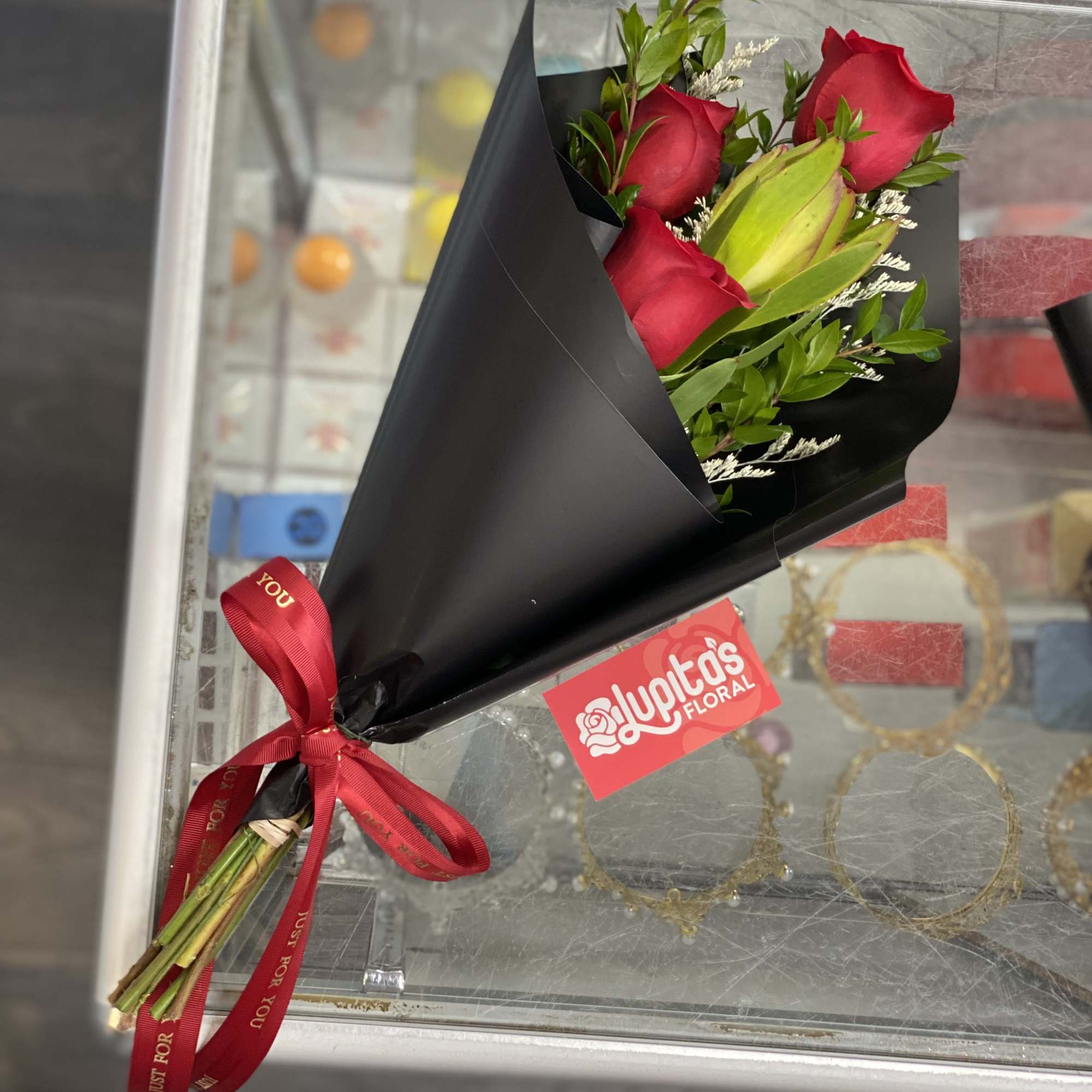 Bouquet of red roses wrapped in black paper with a red ribbon