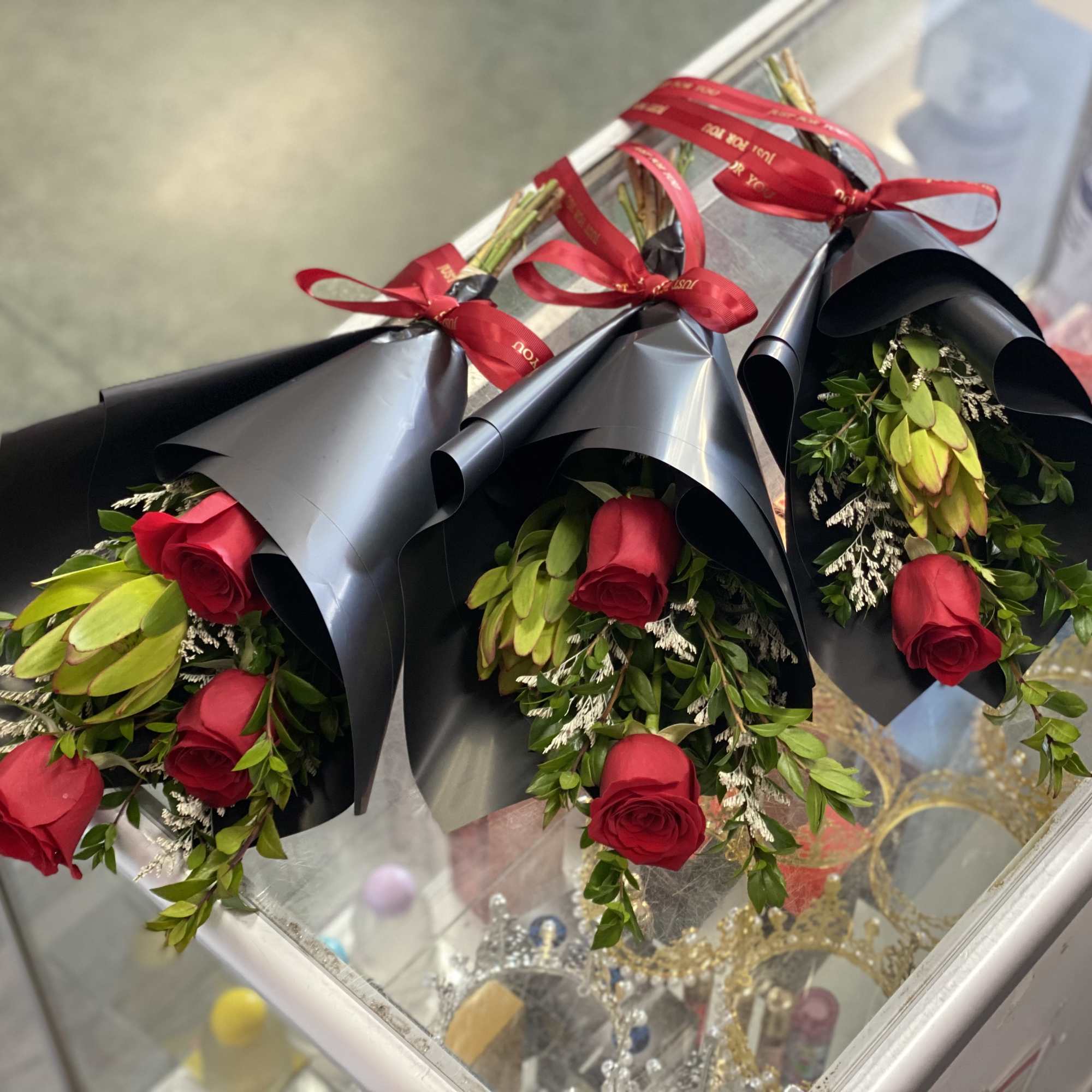 Three red rose bouquets wrapped in black paper with red ribbons