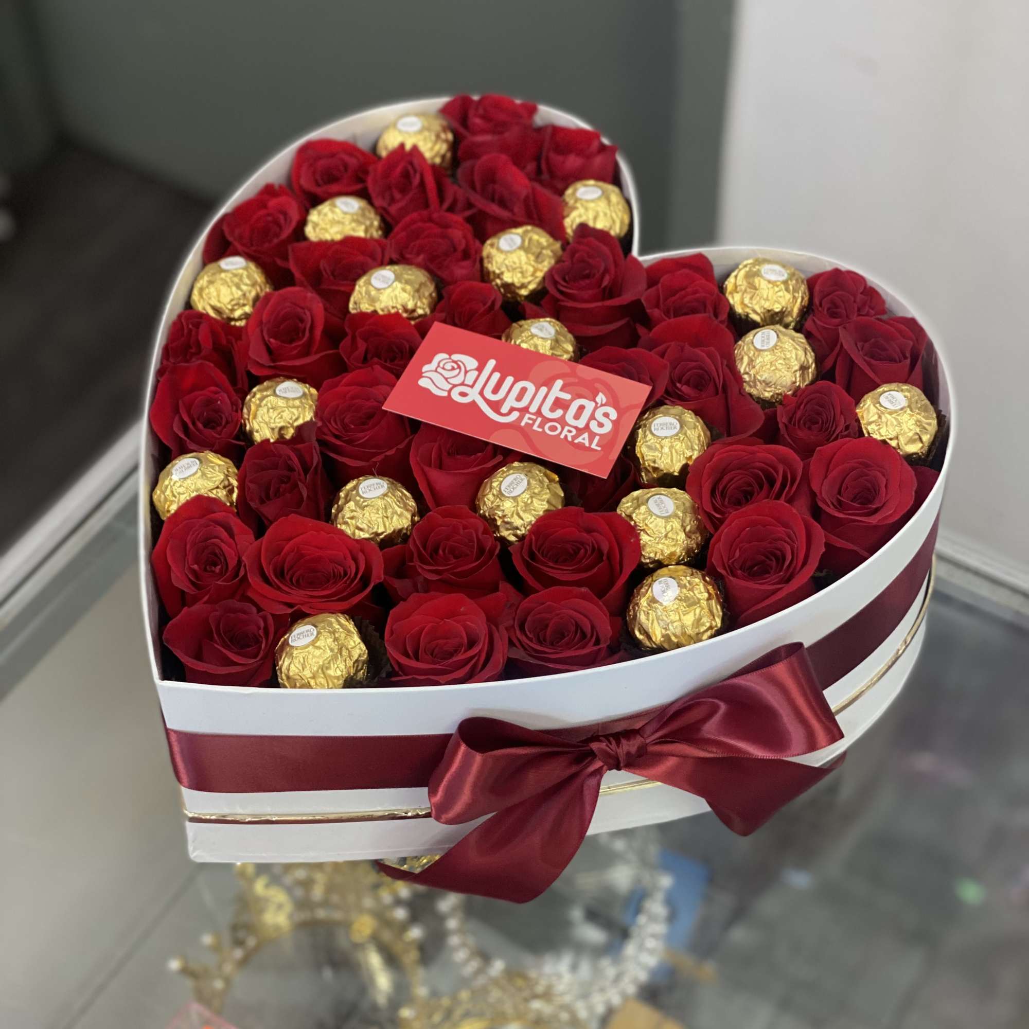 Heart-shaped box of red roses and gold-wrapped chocolates with a satin bow