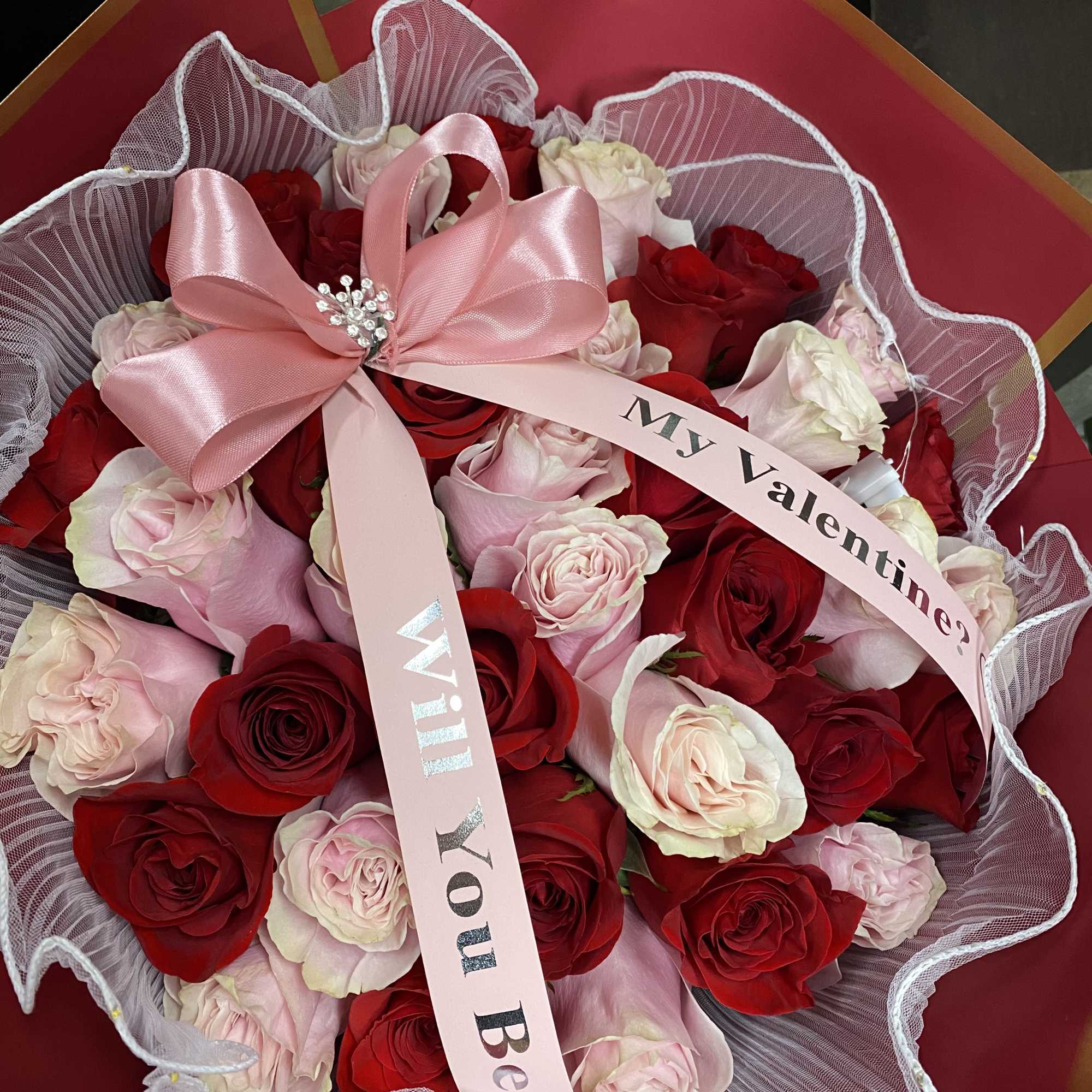 Bouquet of red and pale pink roses with a pink ribbon