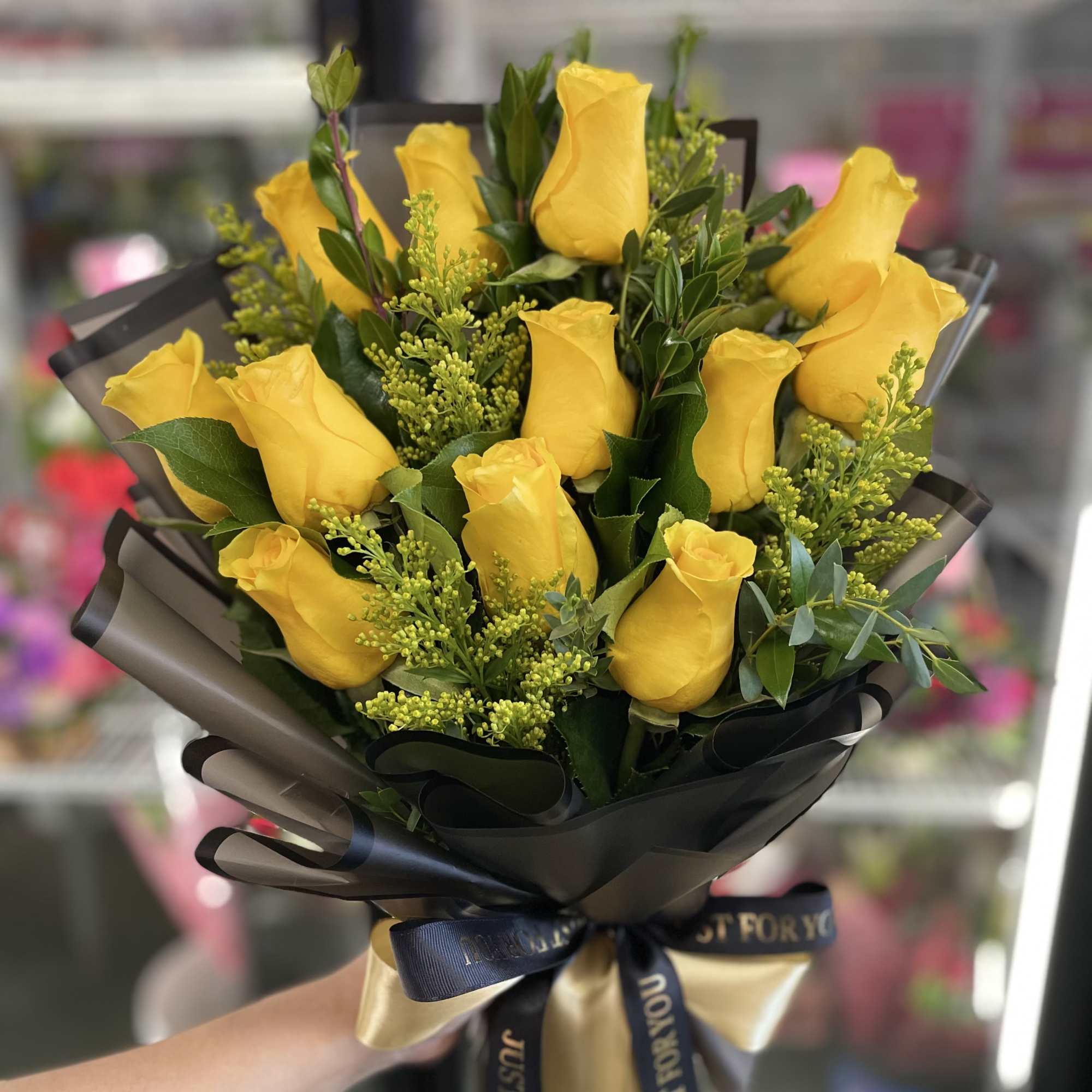 Bouquet of yellow roses wrapped in black paper with a ribbon