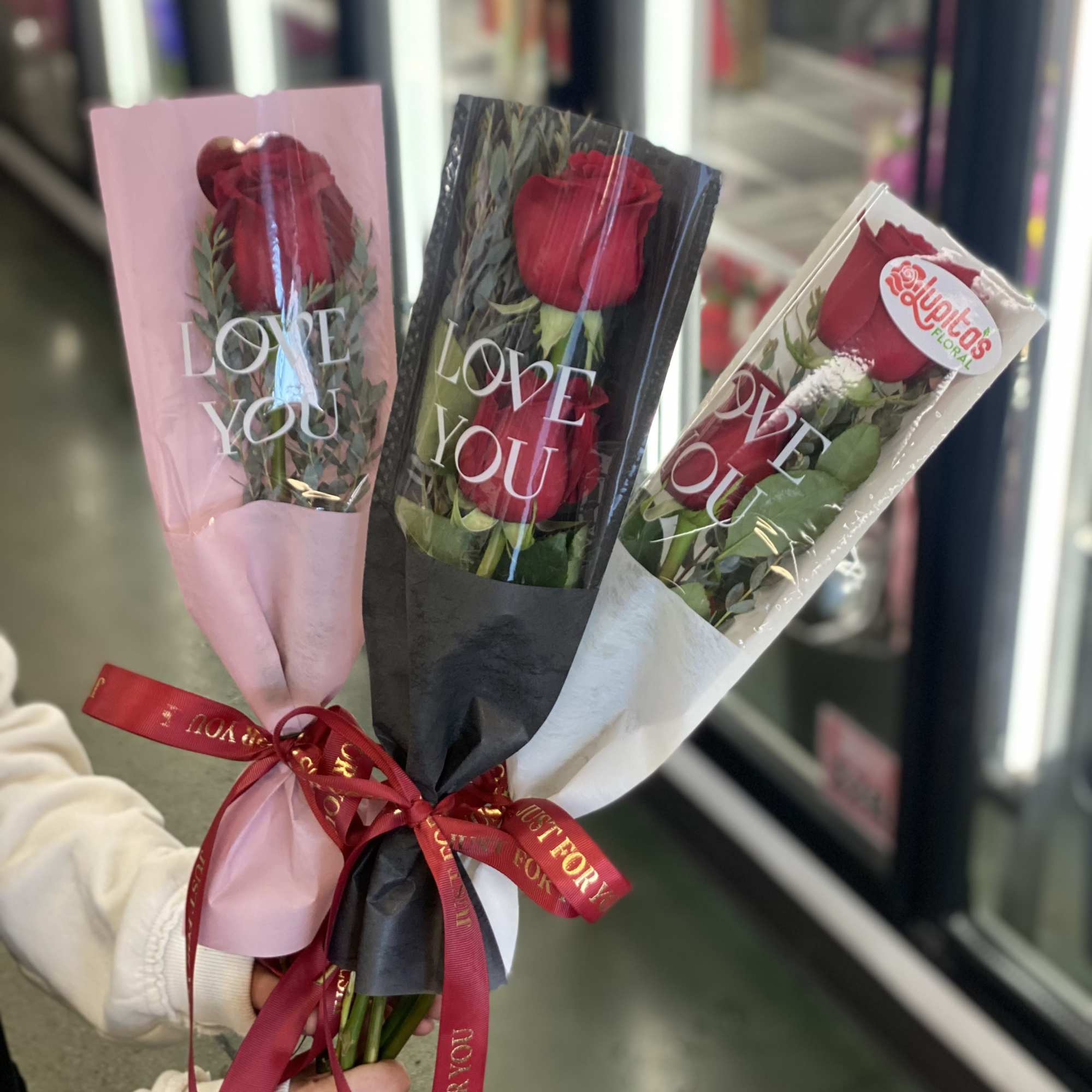 Three wrapped red rose bouquets with "LOVE YOU" sleeves