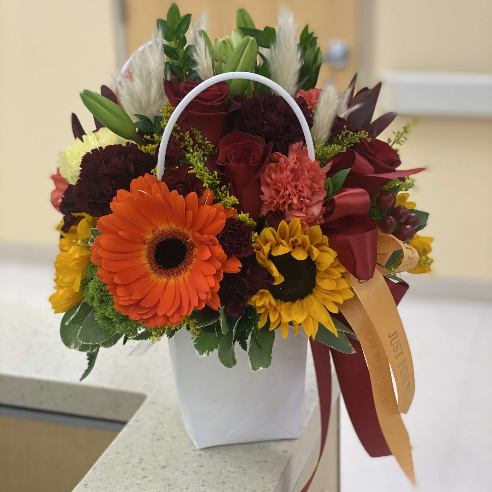 Mixed bouquet with sunflowers, roses, and a white handled container
