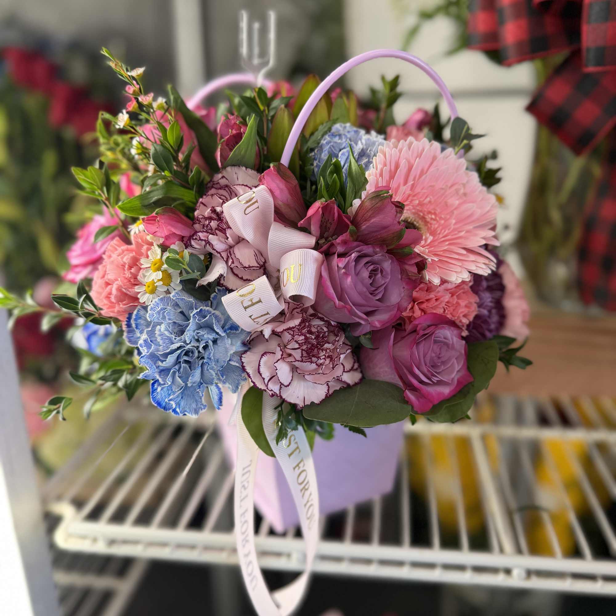 Mixed bouquet in a lavender handled box with pink, purple, and blue flowers