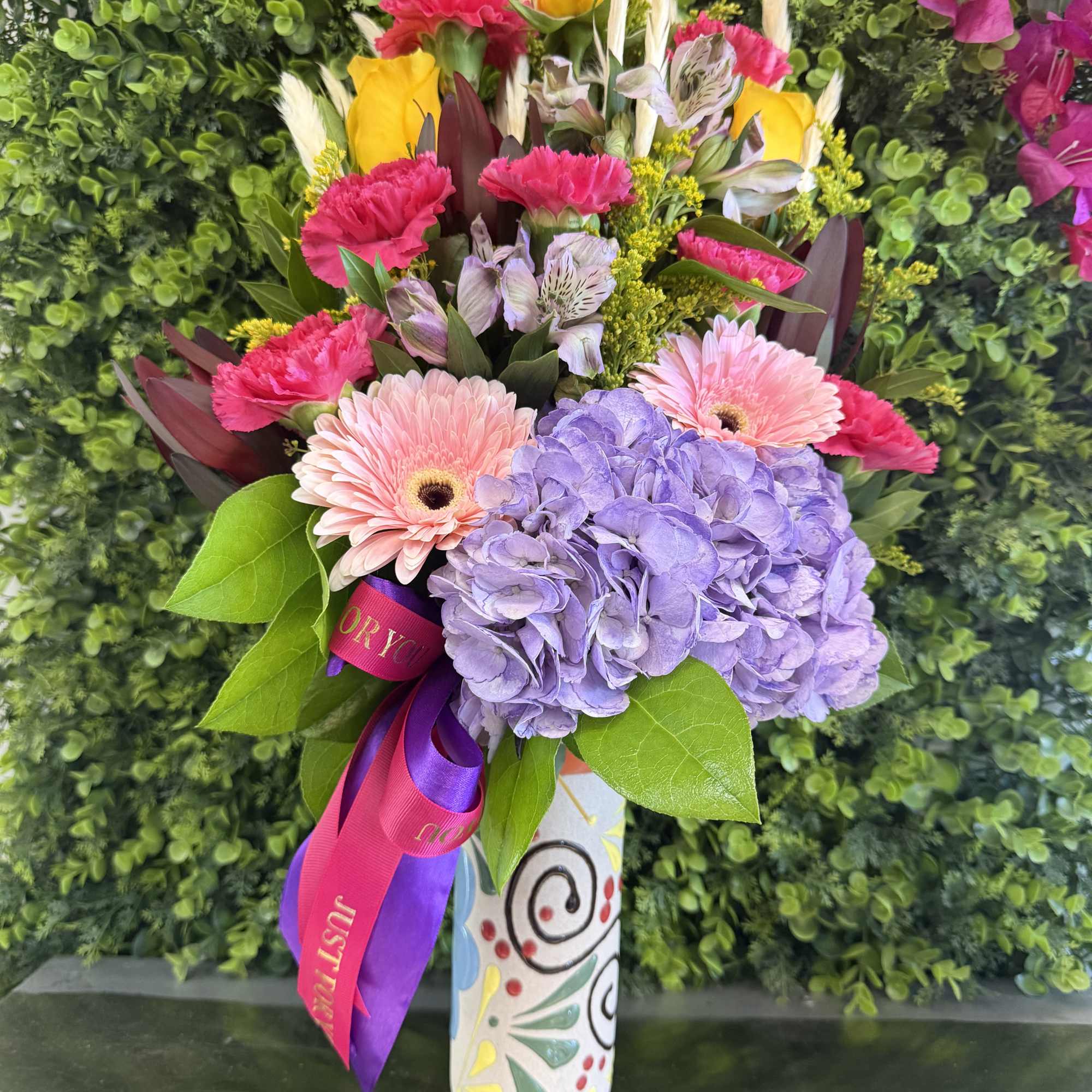 Colorful bouquet with hydrangea, gerbera daisies, carnations, and roses in a painted vase