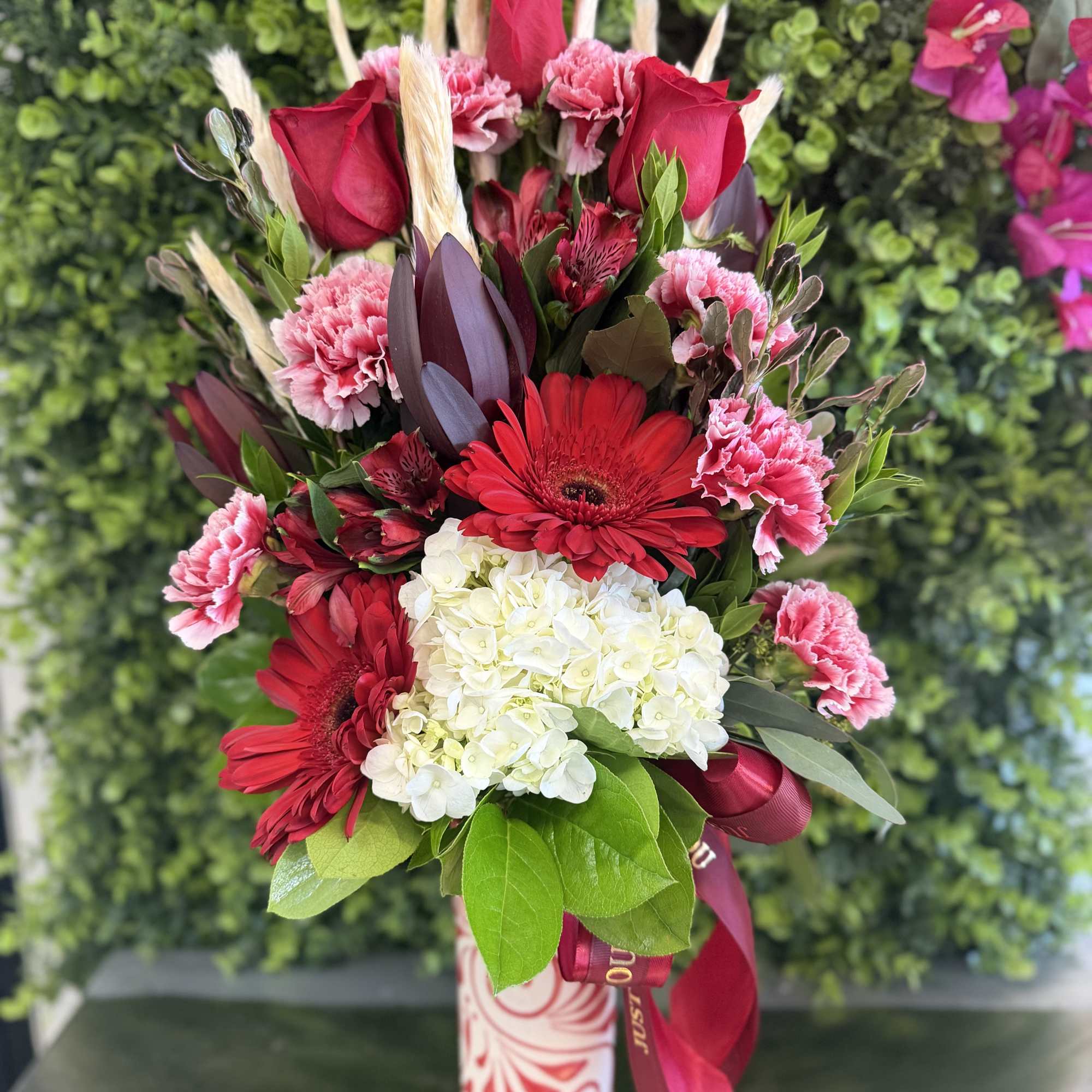 Red and pink mixed bouquet in a patterned vase