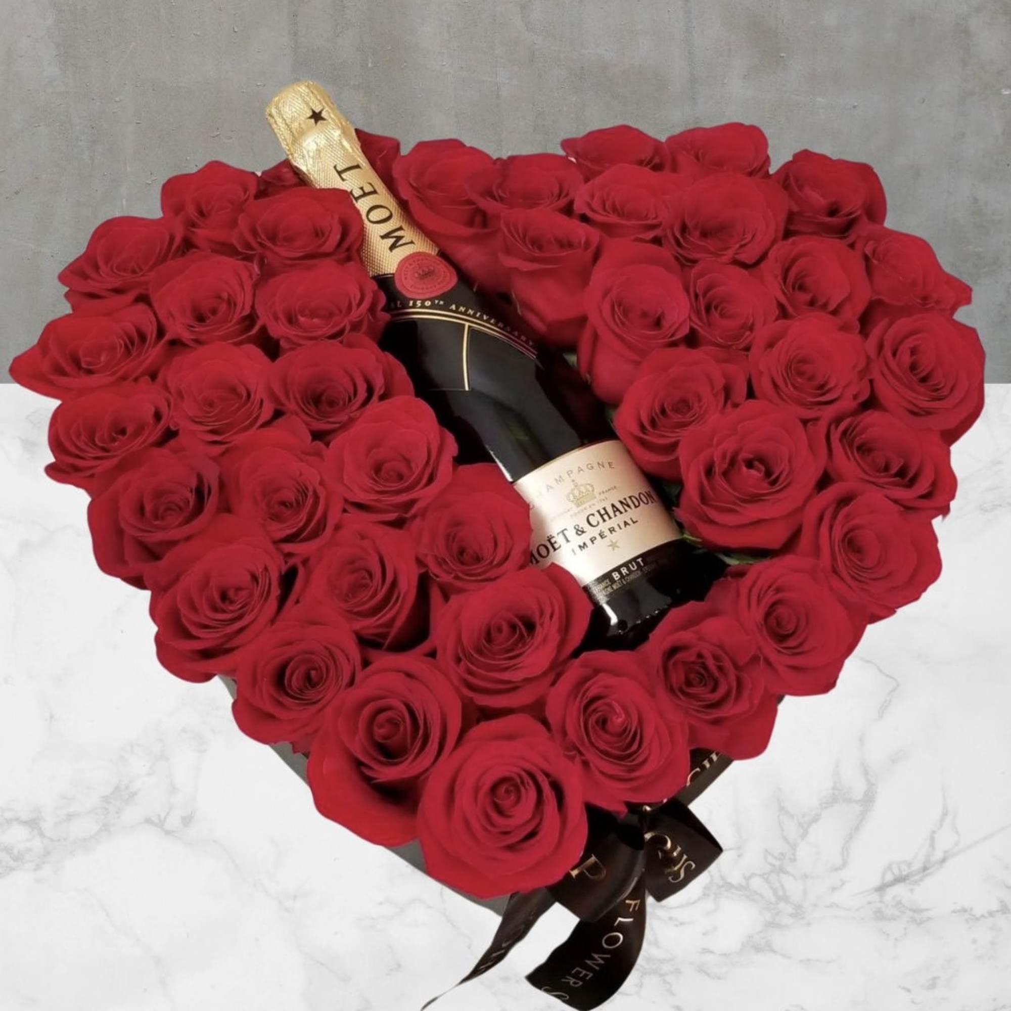 Heart-shaped bouquet of red roses with a champagne bottle in the center