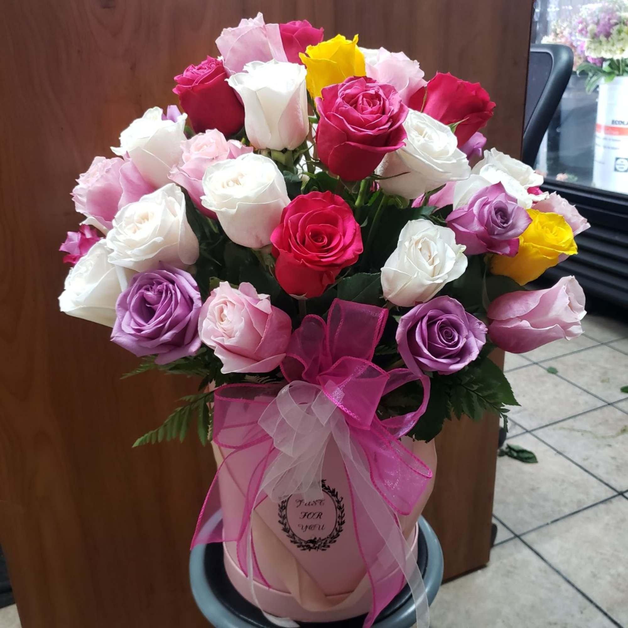 Bouquet of multicolored roses in a pink hatbox with ribbon