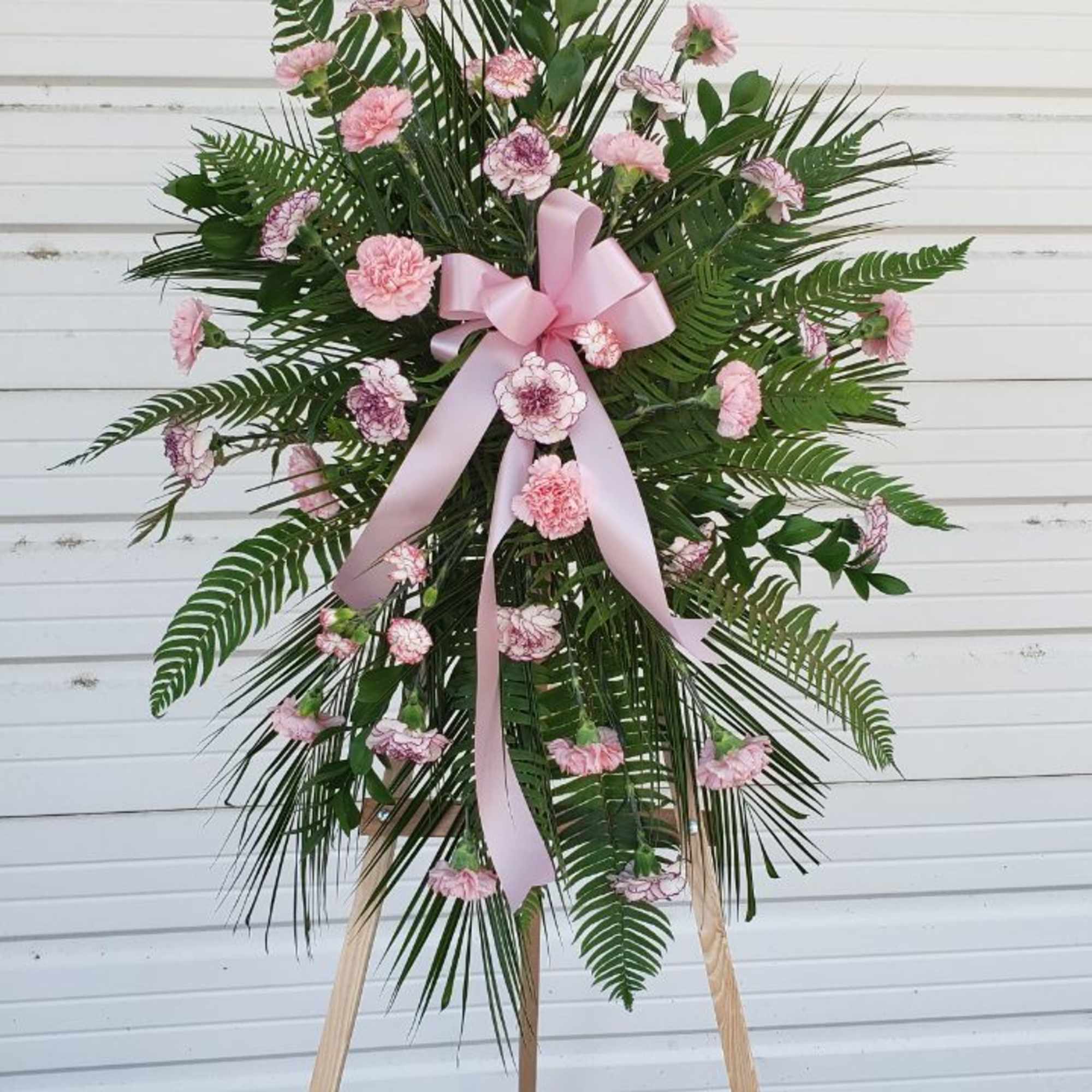 Standing floral spray with pink carnations and a pink ribbon on an easel, photo 2 of 2