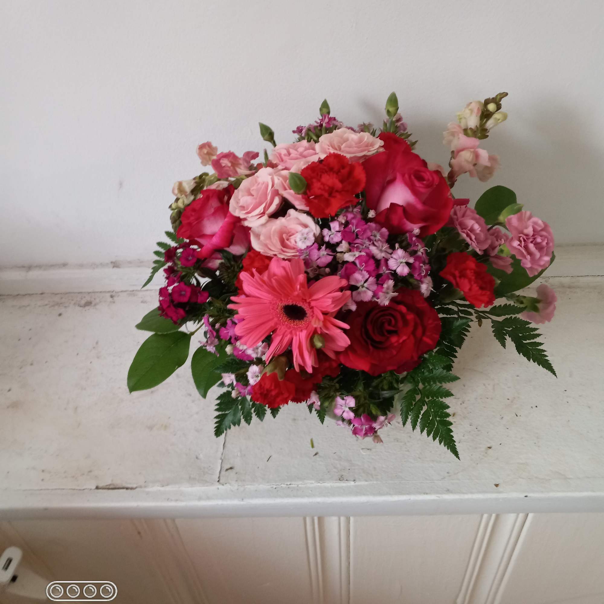 Mixed bouquet of pink and red flowers on a white surface