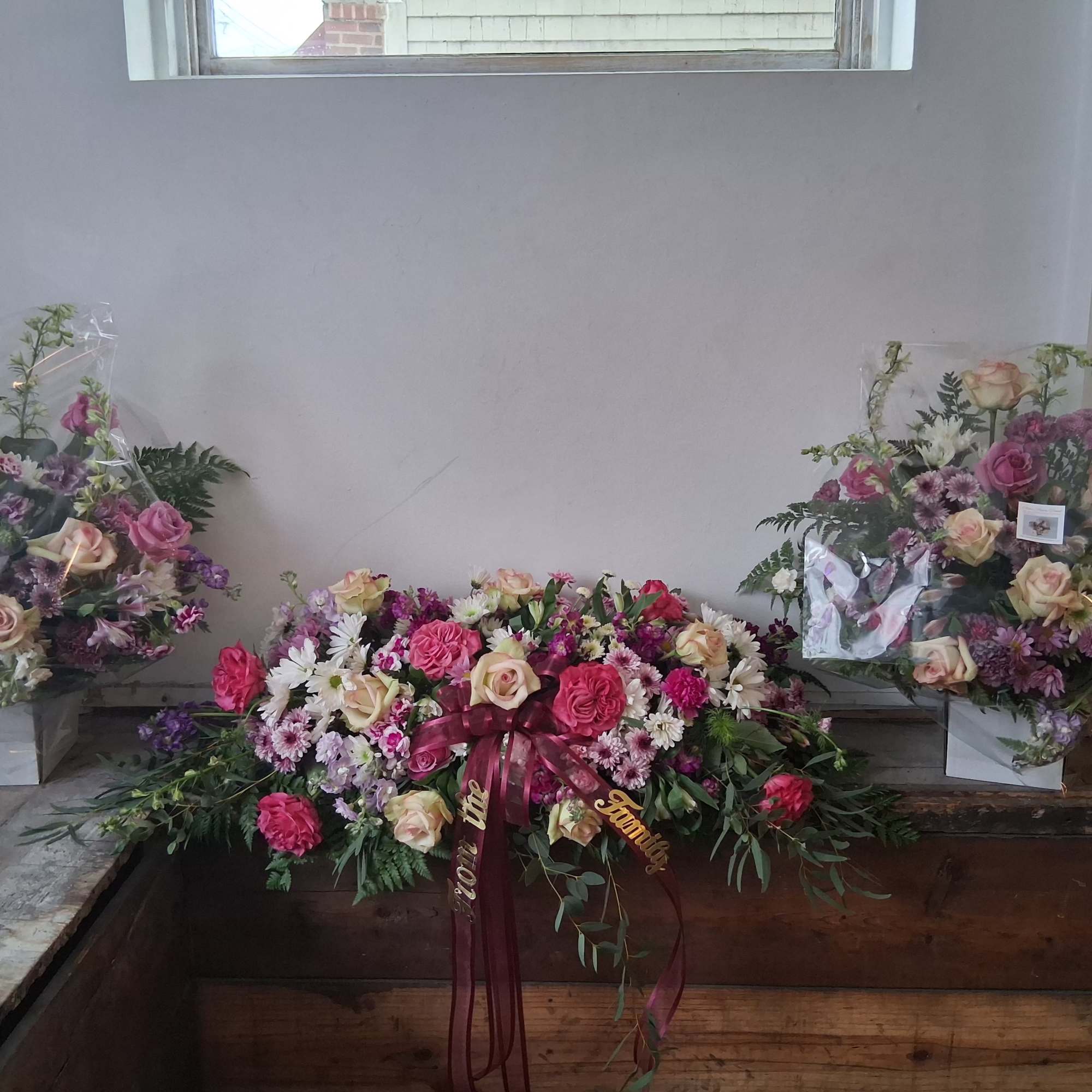Three floral arrangements with pink and cream roses and daisies in white containers