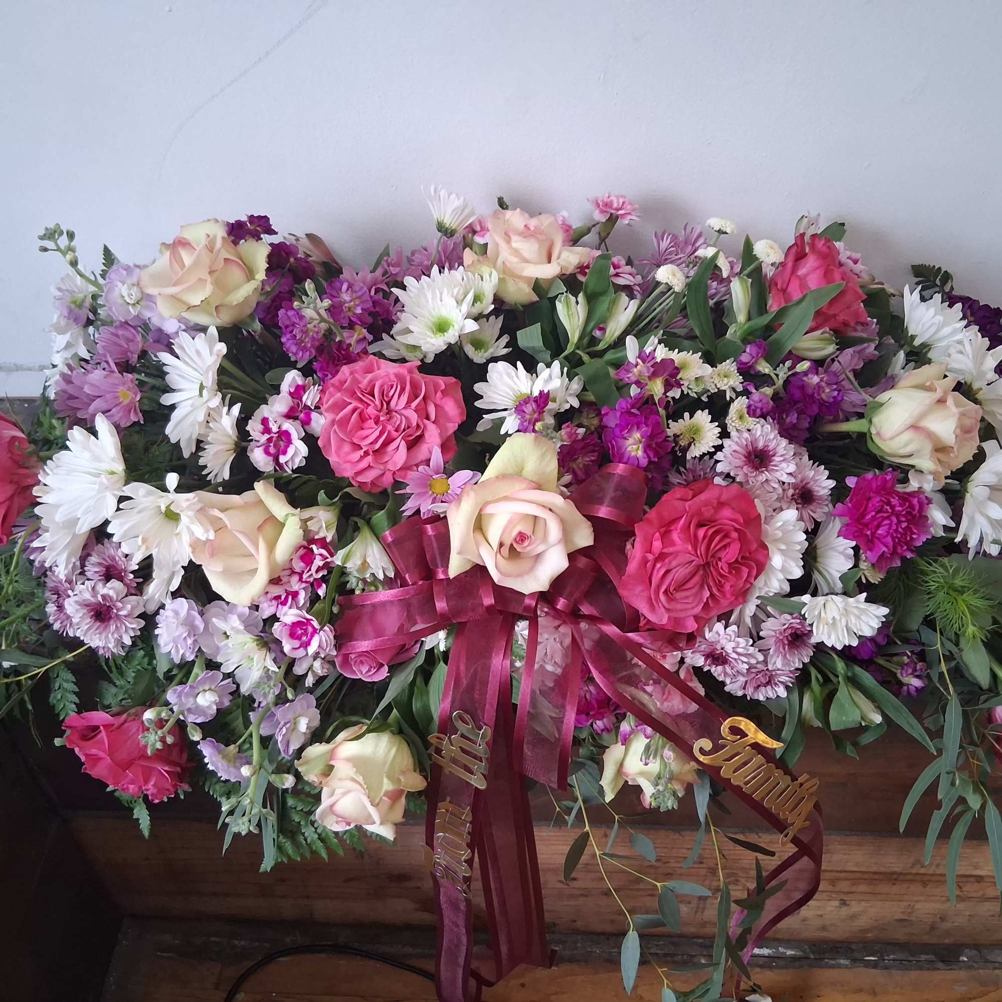 Large pink and white floral casket spray with ribbon accents