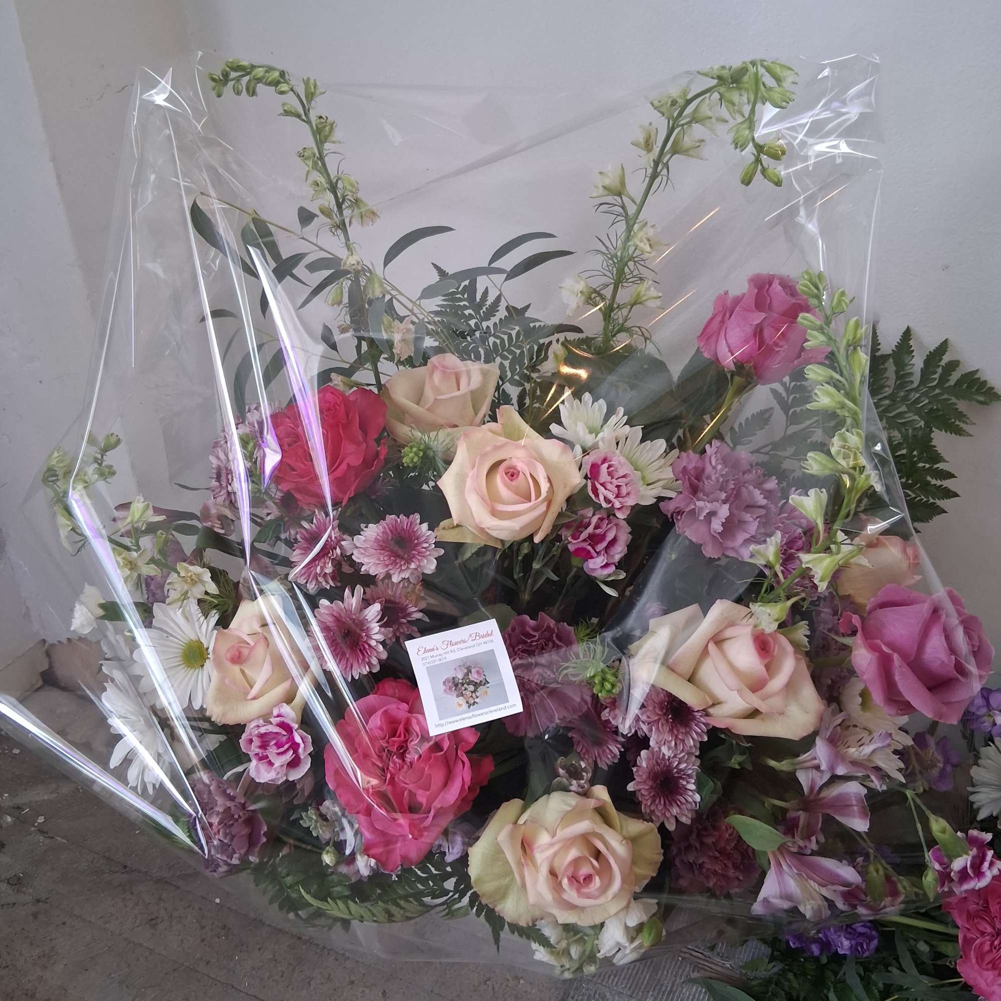 Mixed bouquet of pink and cream roses with daisies in clear wrap