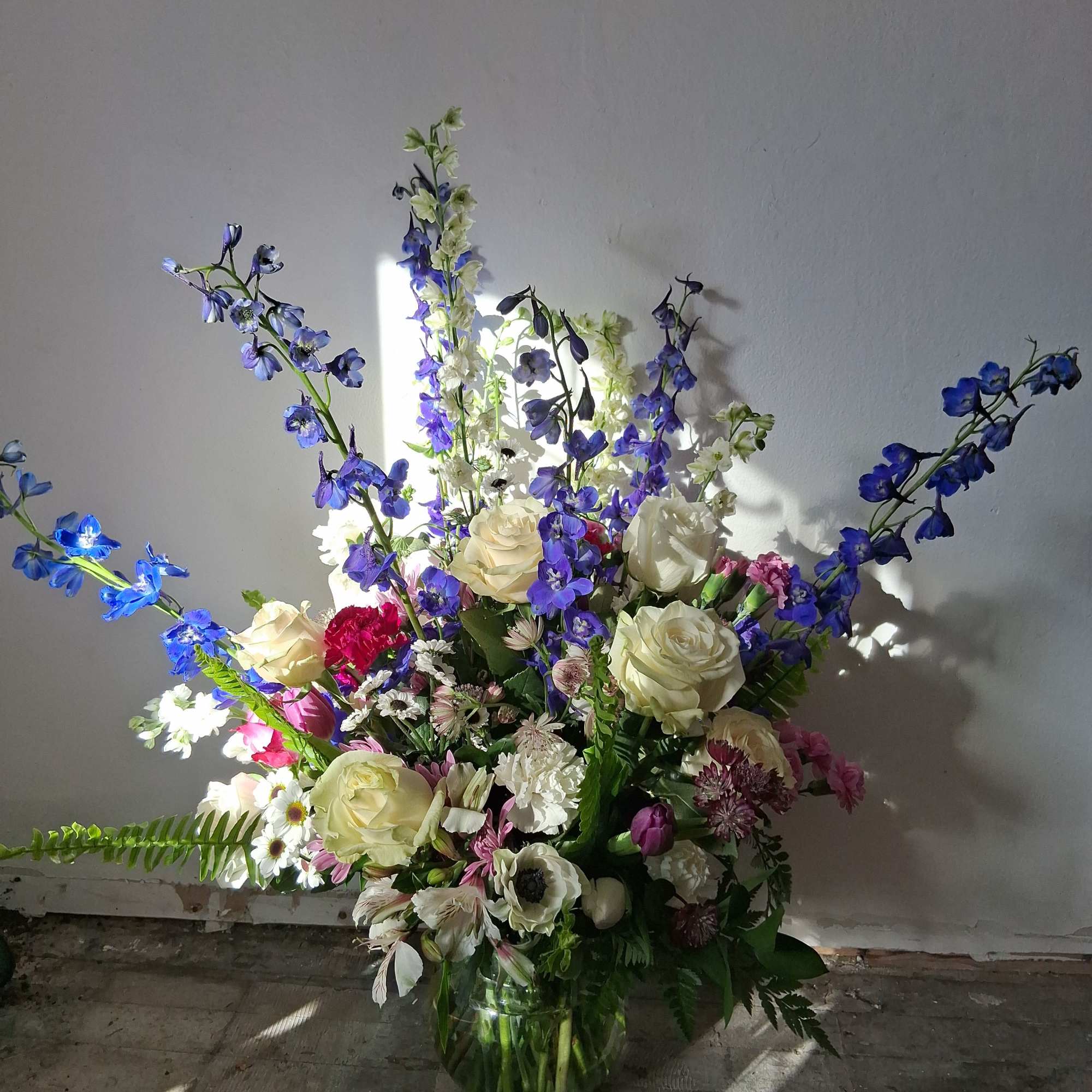 Tall mixed bouquet in a glass vase with blue and white flowers