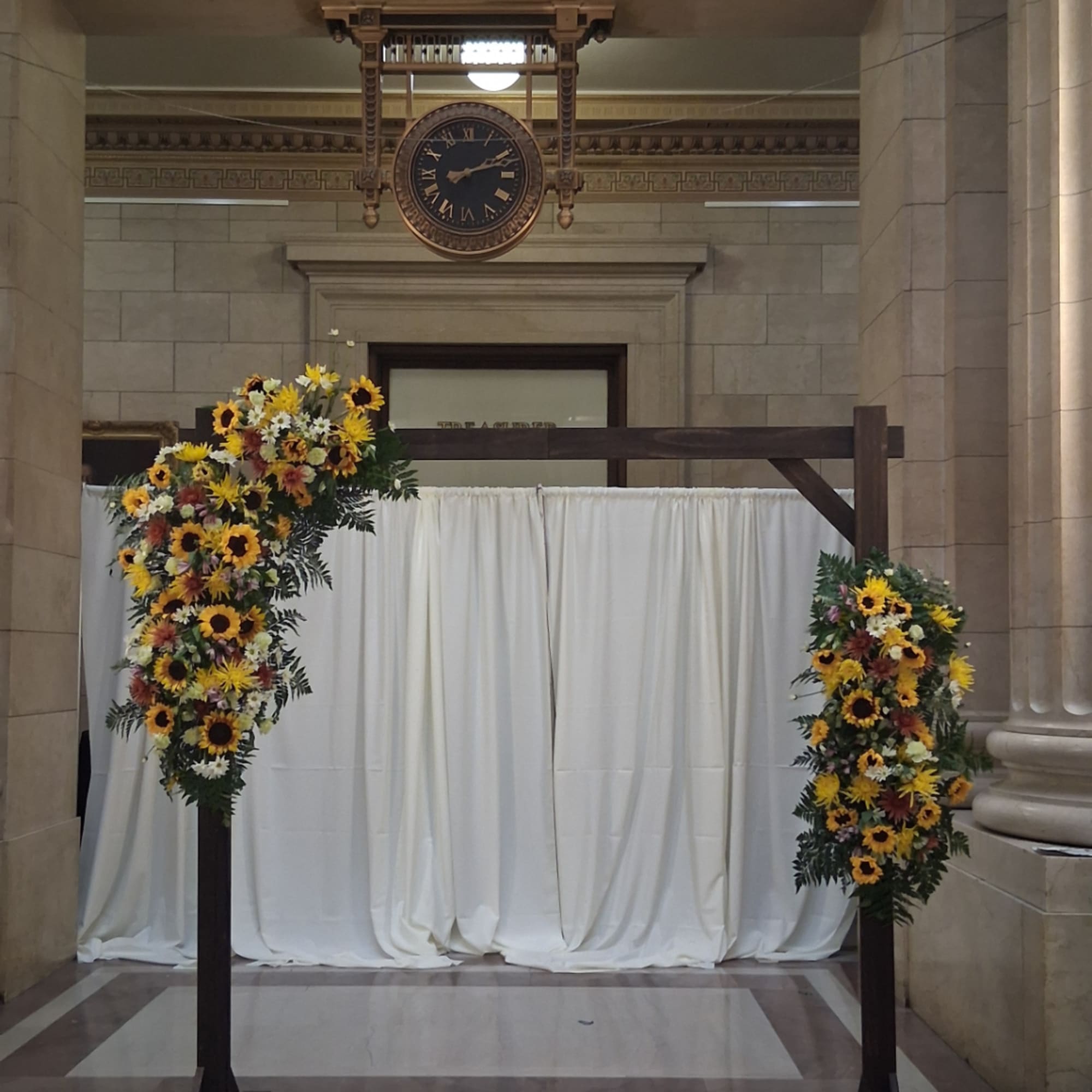 Wedding arch decorated with sunflower and daisy arrangements