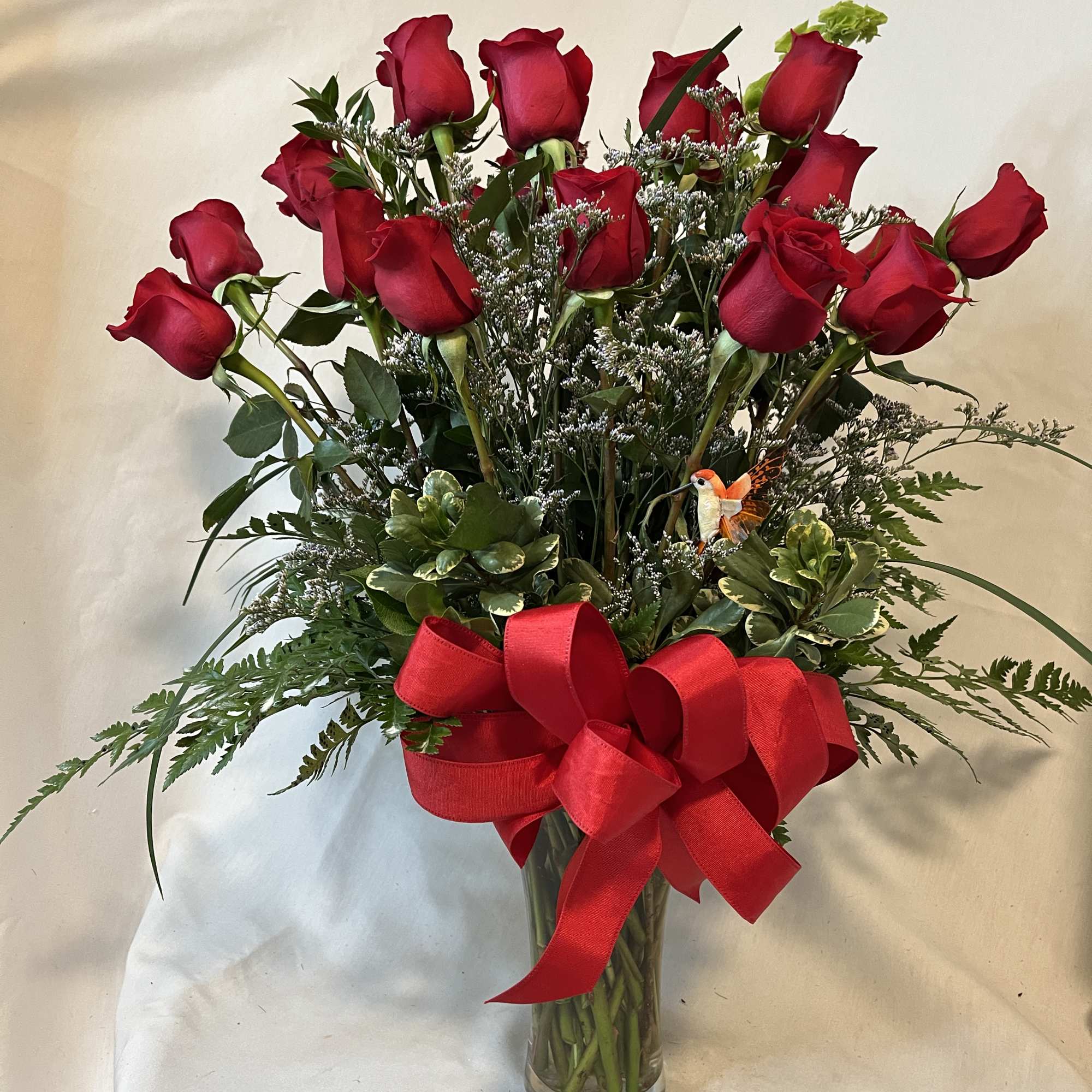 Red roses in a glass vase with a large red ribbon bow
