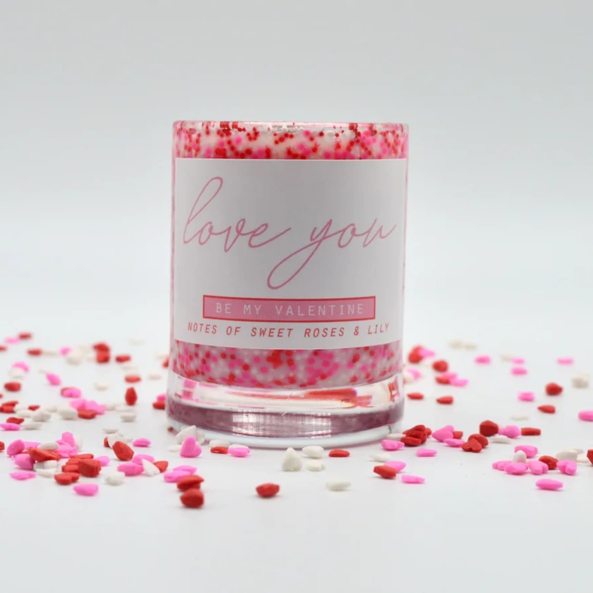 Pink candle in a glass jar with confetti around it