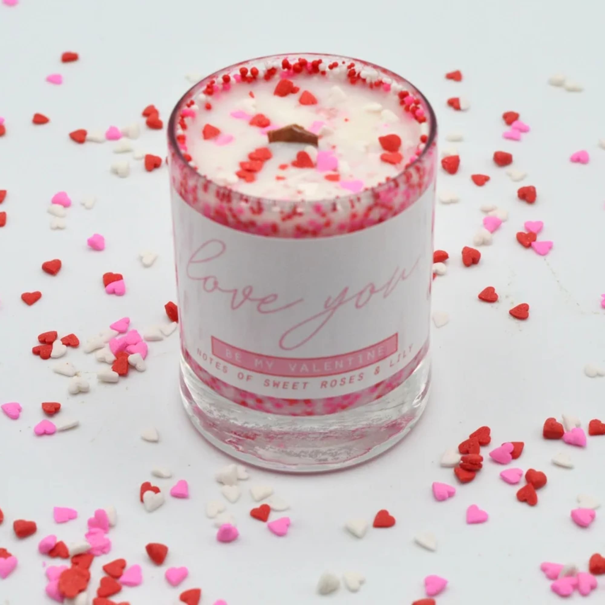 Pink and red heart confetti around a scented candle in a glass jar