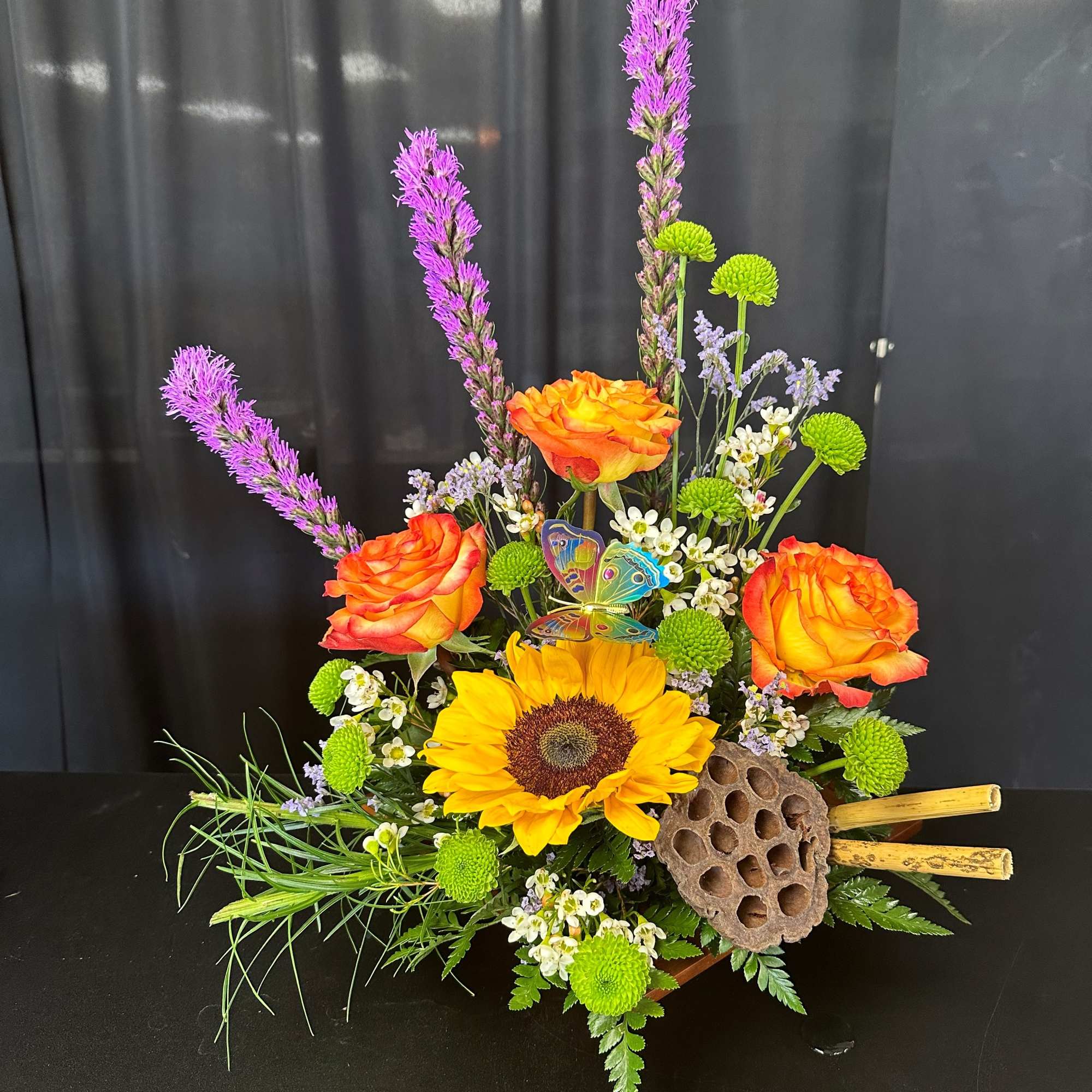 Colorful floral arrangement with sunflowers, orange roses, and purple spikes