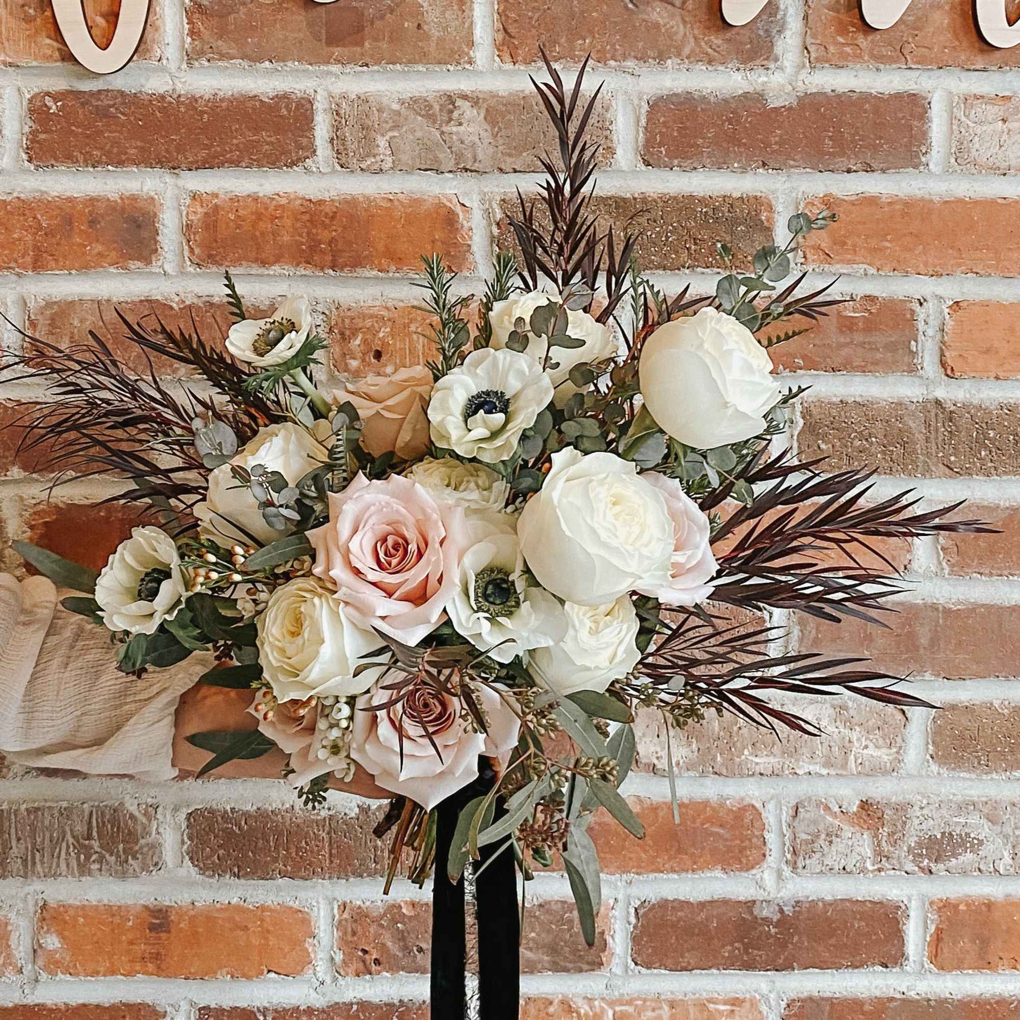 Bouquet of blush and white roses with anemones and dark foliage