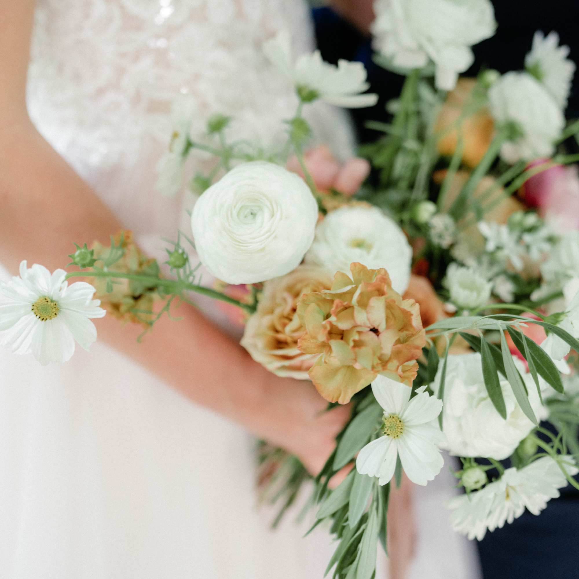 Bride holding a white and peach bouquet with daisy-like blooms