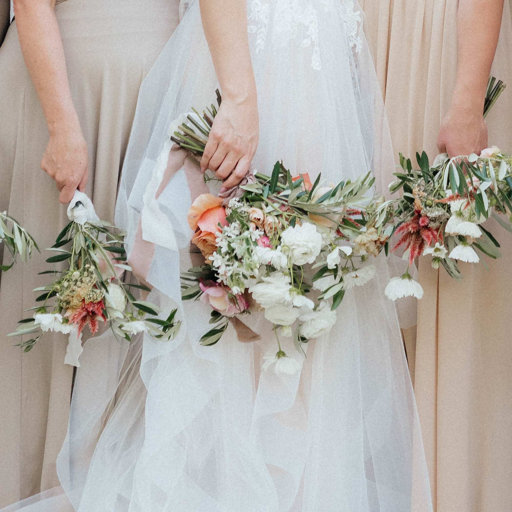 Bride and bridesmaids holding floral bouquets and wreaths