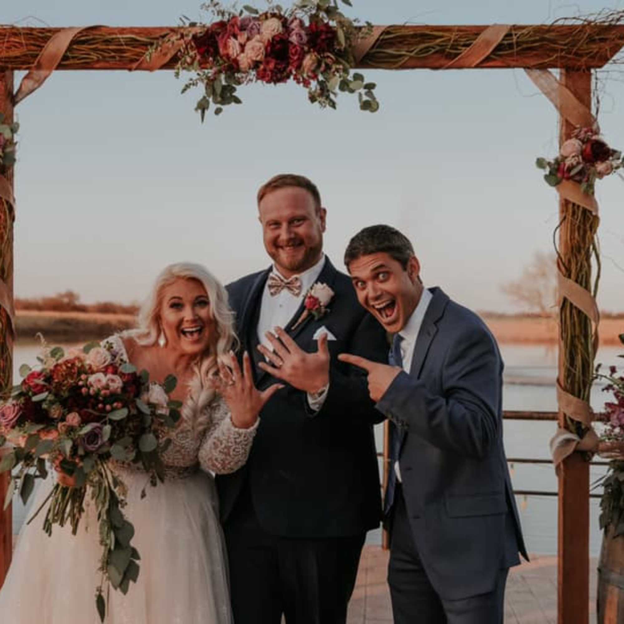 Wedding couple posing under a floral arch with bouquets and arrangements