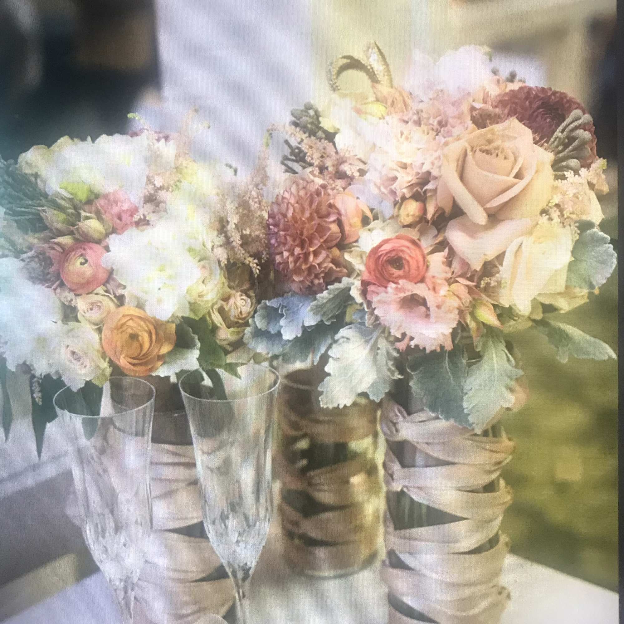 Two pastel floral bouquets in tall glass vases with ribbon wrap
