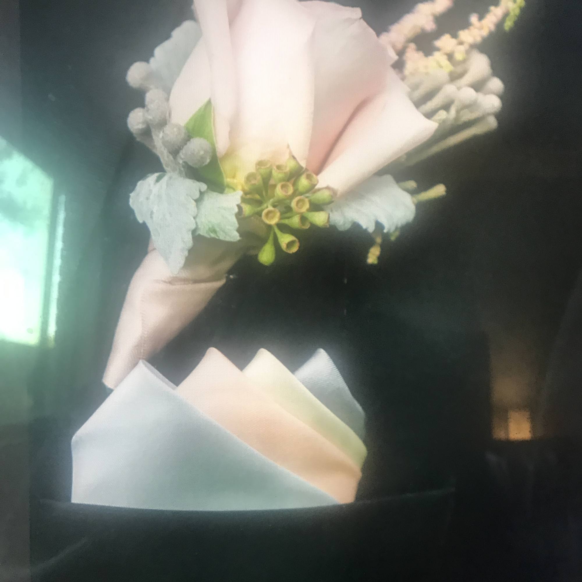 Small pastel bouquet with pale pink blooms and blue-gray filler wrapped in paper