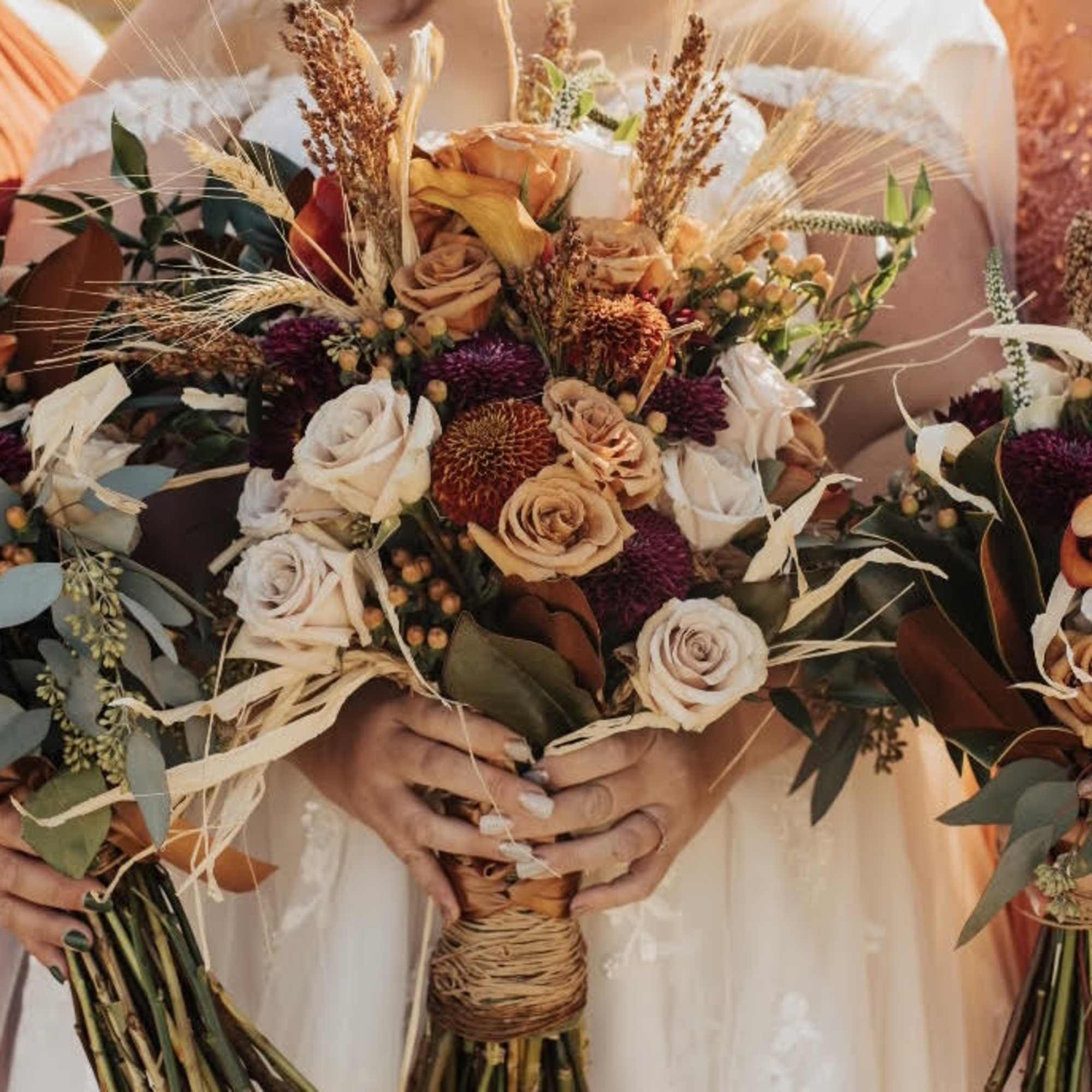 Three bridal bouquets with peach and cream roses and dried accents