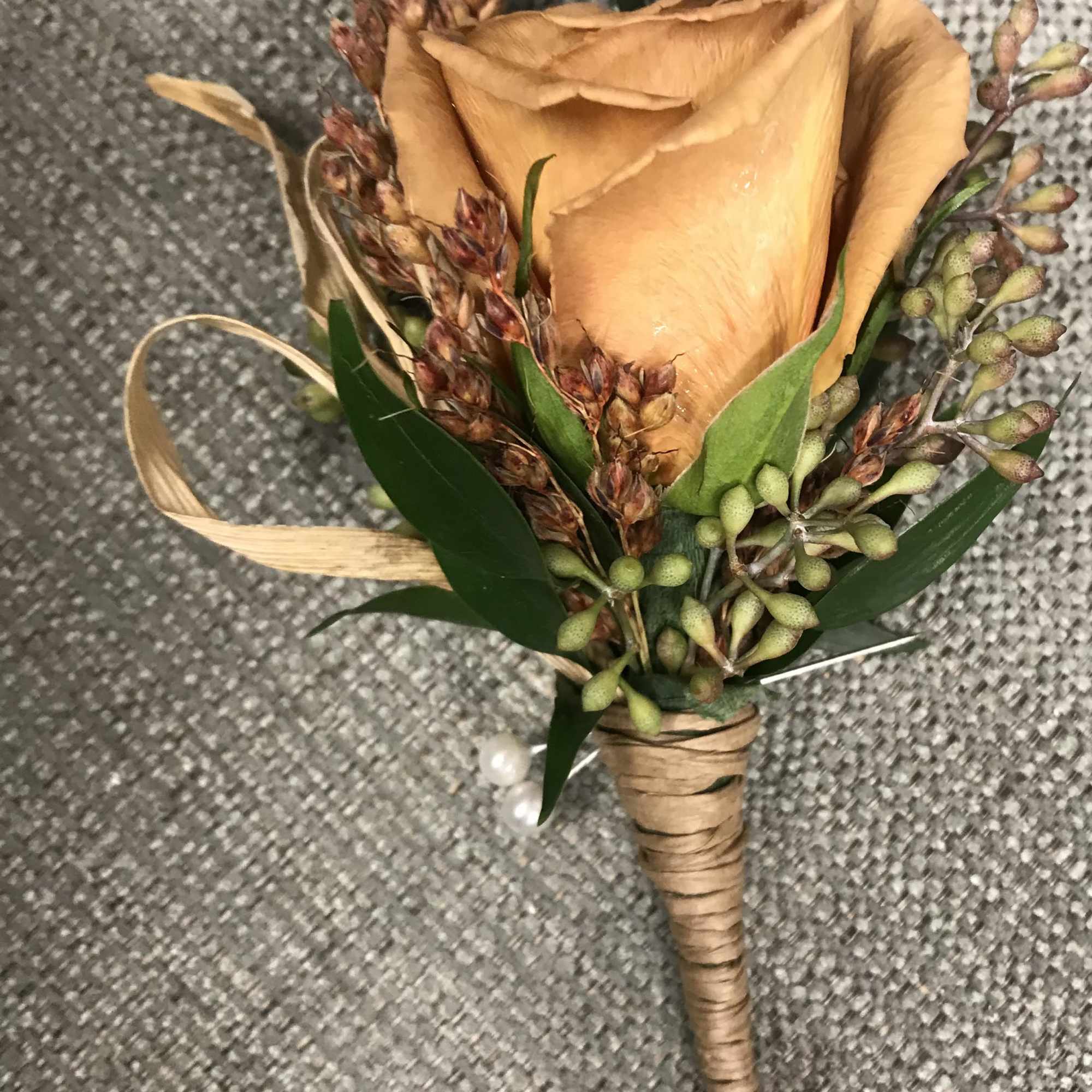 Peach rose boutonniere with green accents and wrapped stem