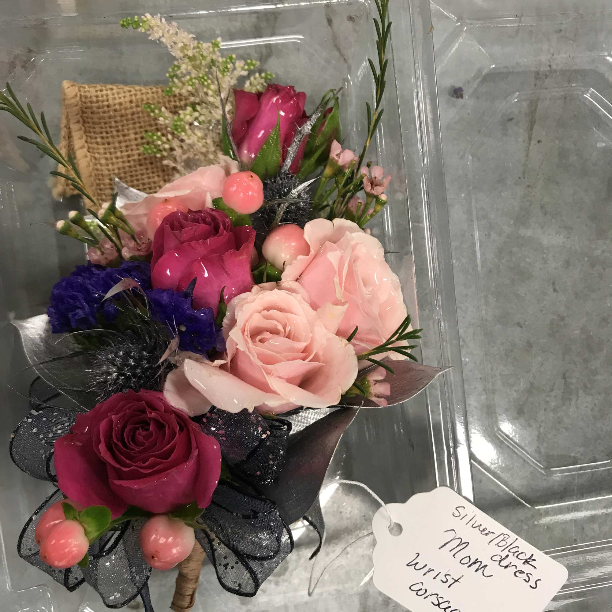 Small bouquet of pink and magenta roses in a clear plastic box
