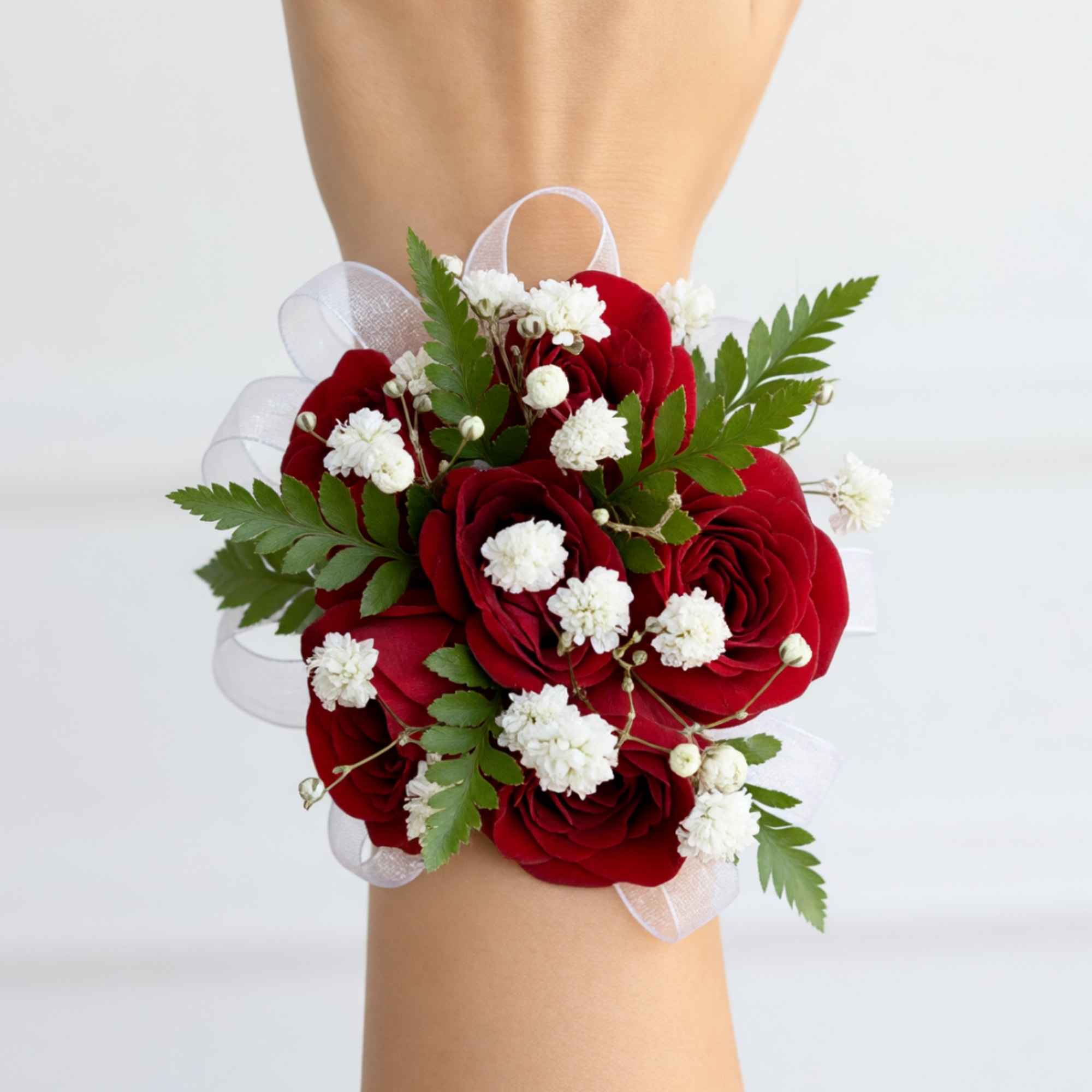 Red rose wrist corsage with white filler flowers and ribbon