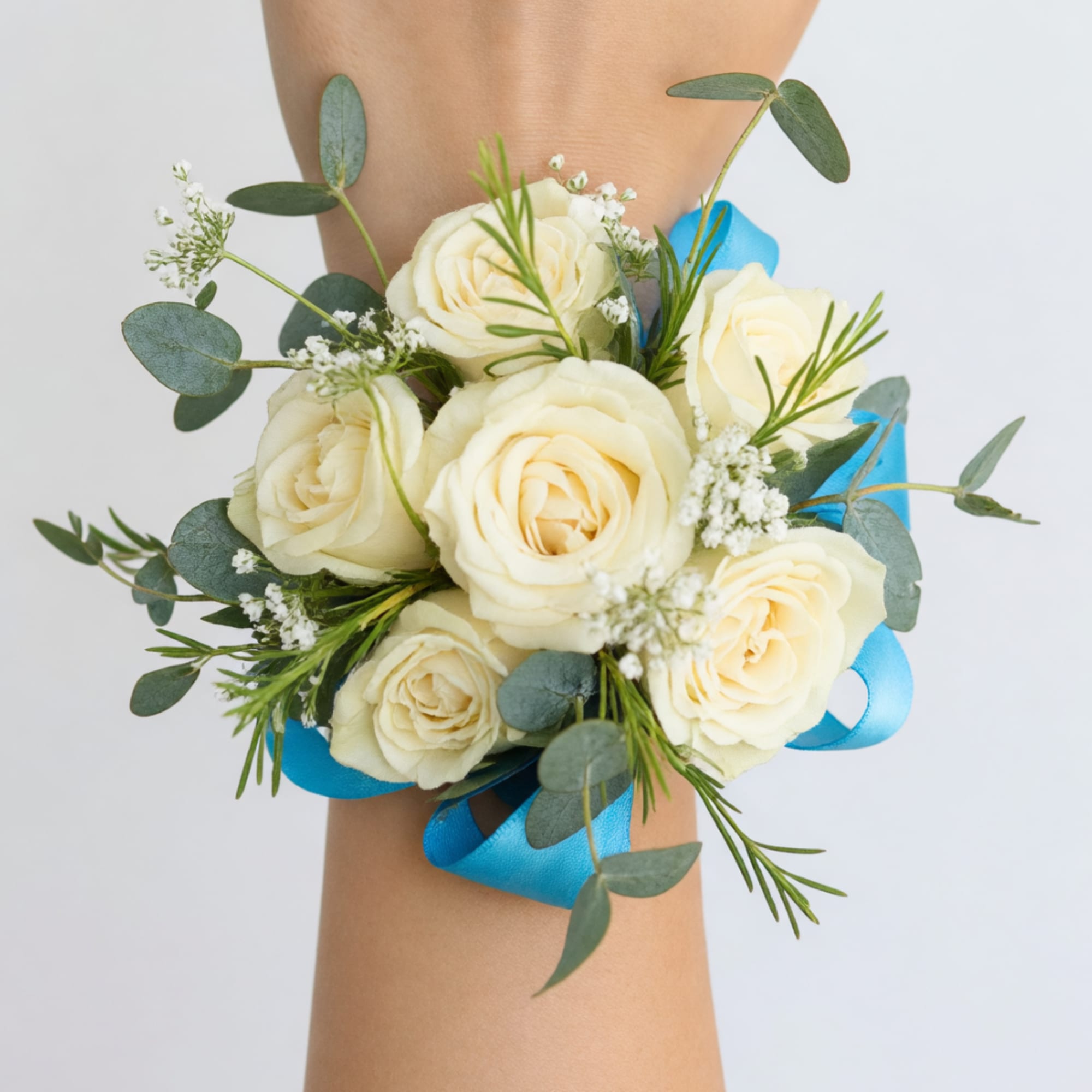 Cream rose wrist corsage with blue ribbon and greenery
