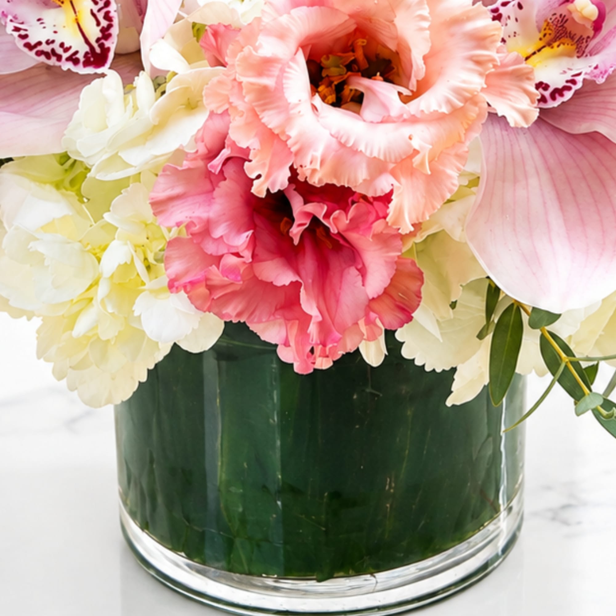 Pink and white flowers arranged in a clear glass vase