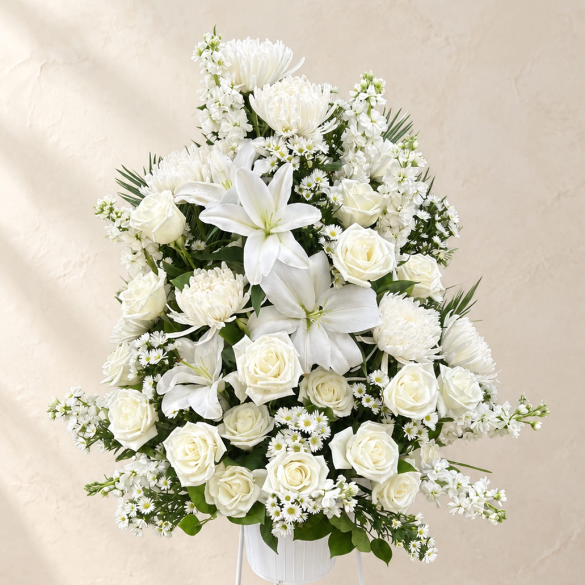 White floral arrangement with roses, lilies, and daisies in a white vase