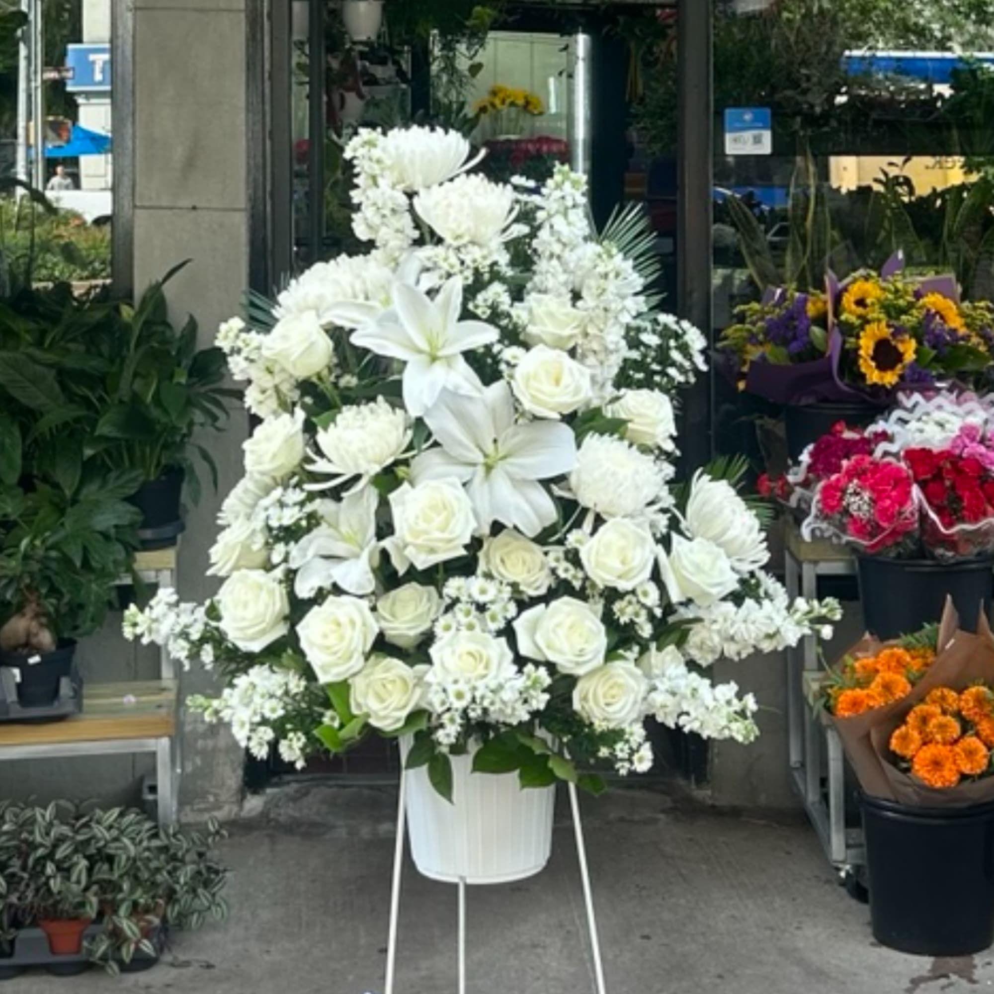 Large white floral arrangement in a white container on a stand