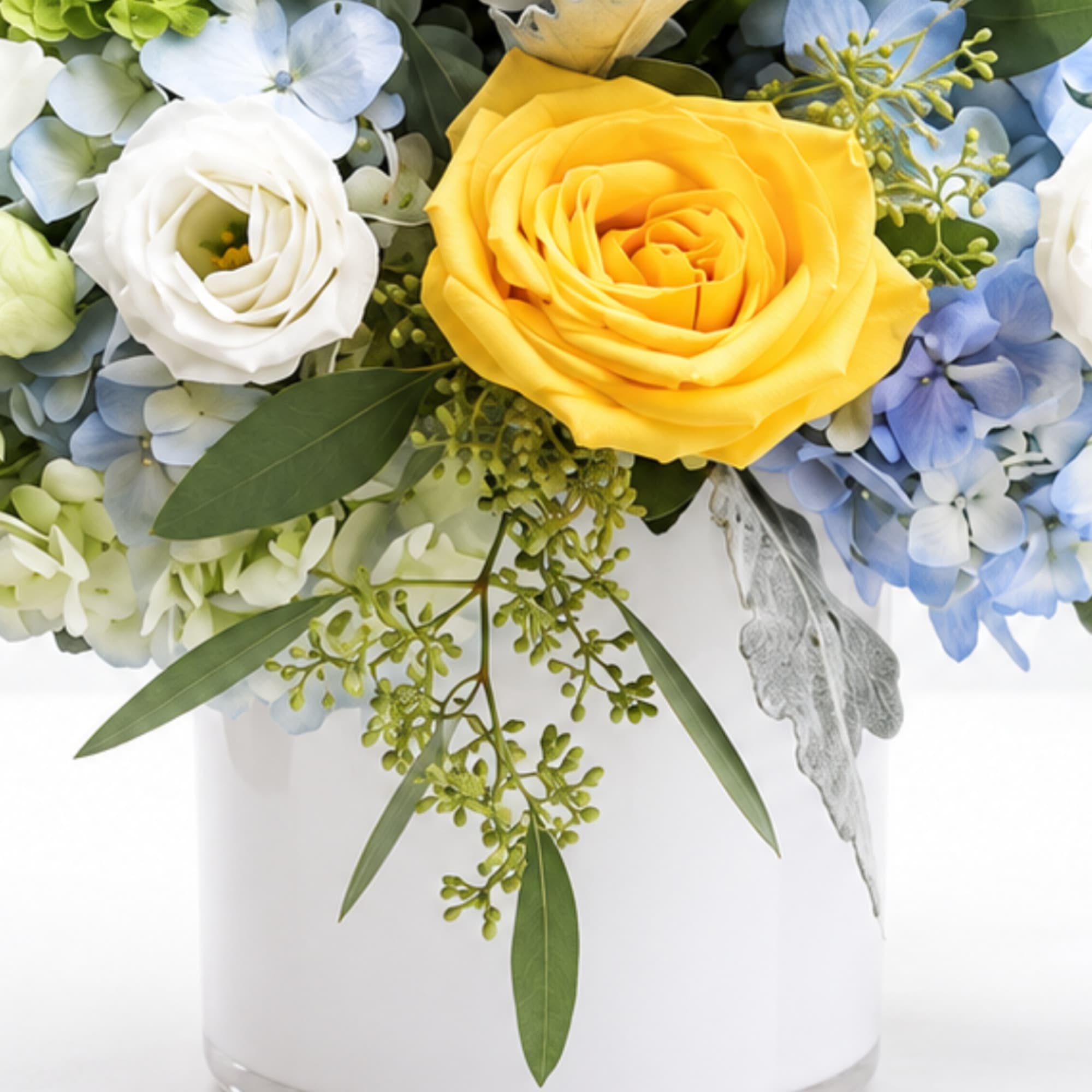 Yellow and white roses with blue hydrangeas in a white vase