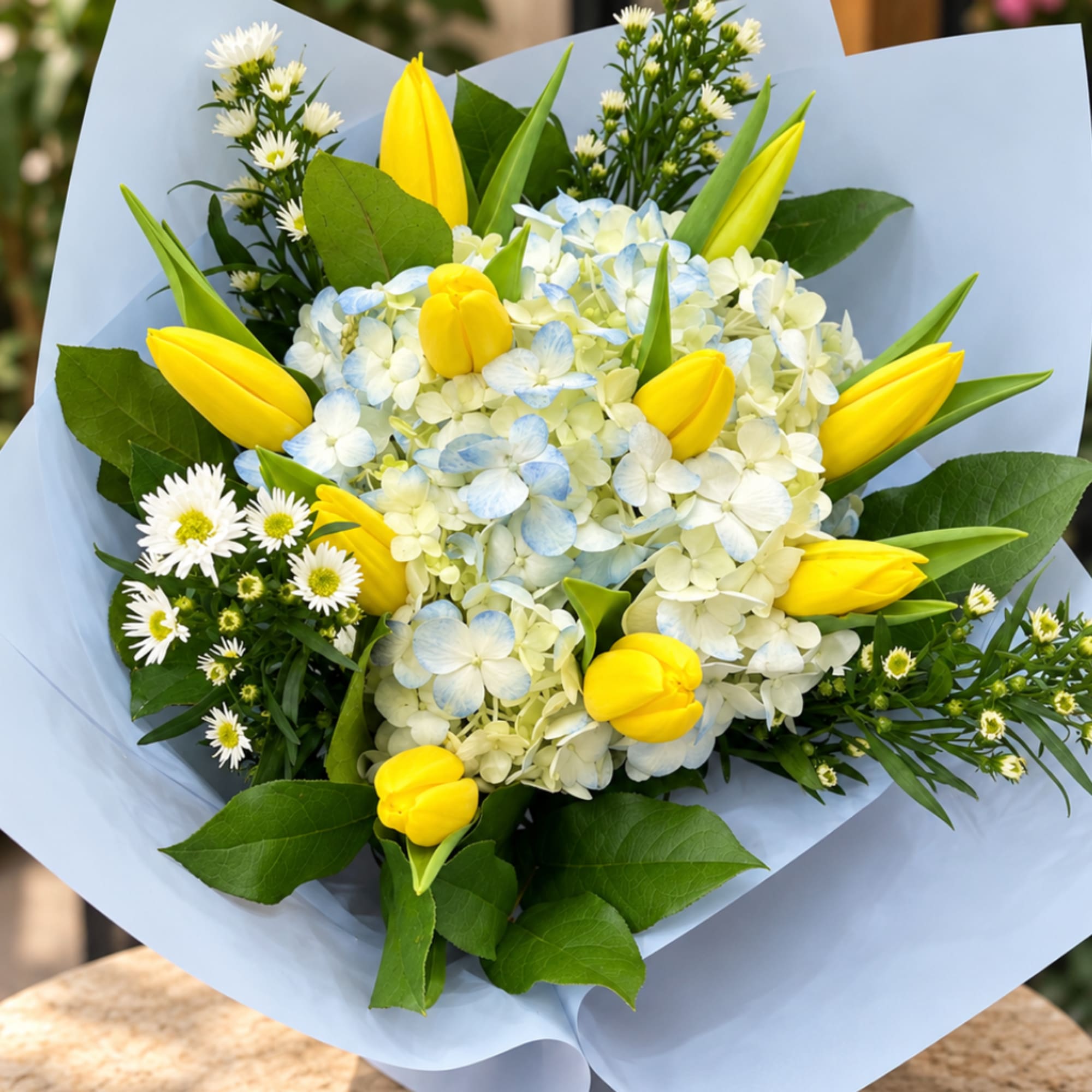 Bouquet of yellow tulips and pale blue hydrangea with white daisies