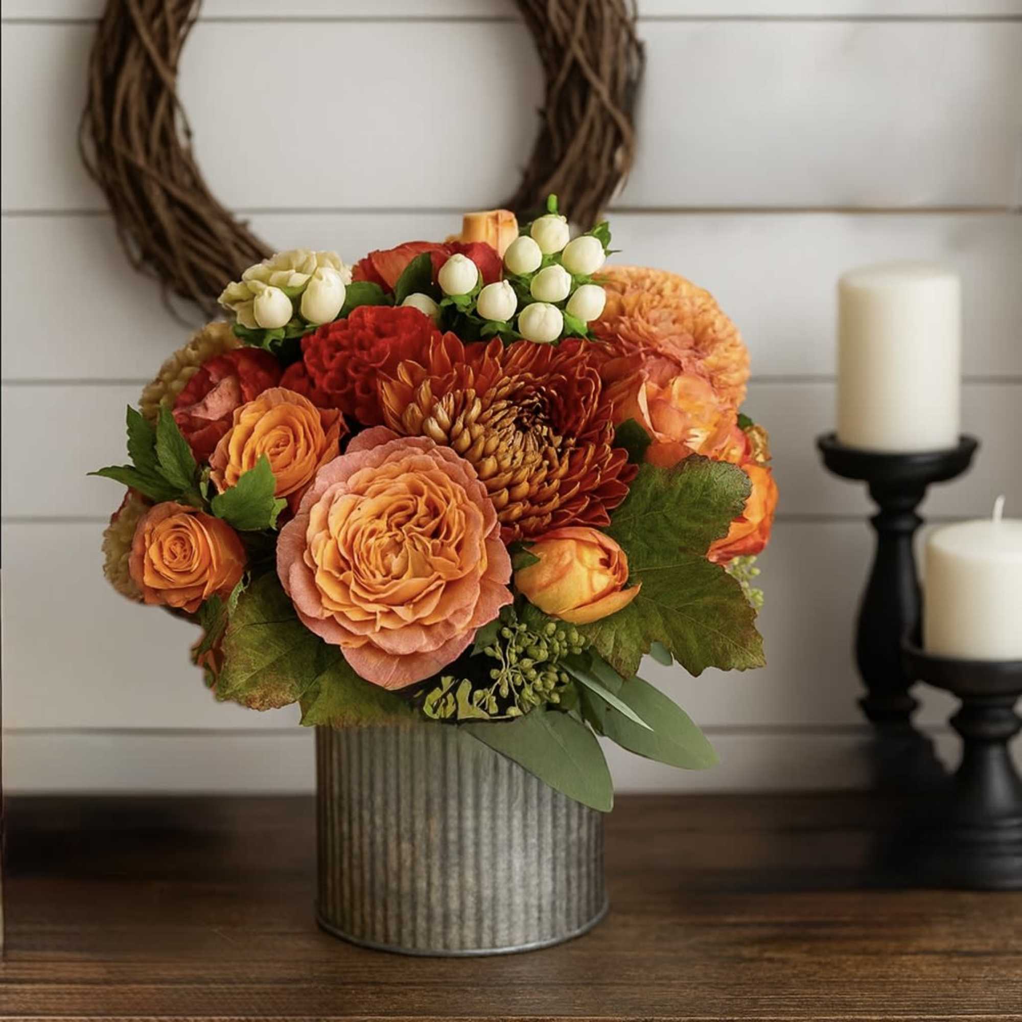 Orange and red floral arrangement in a ribbed metal container